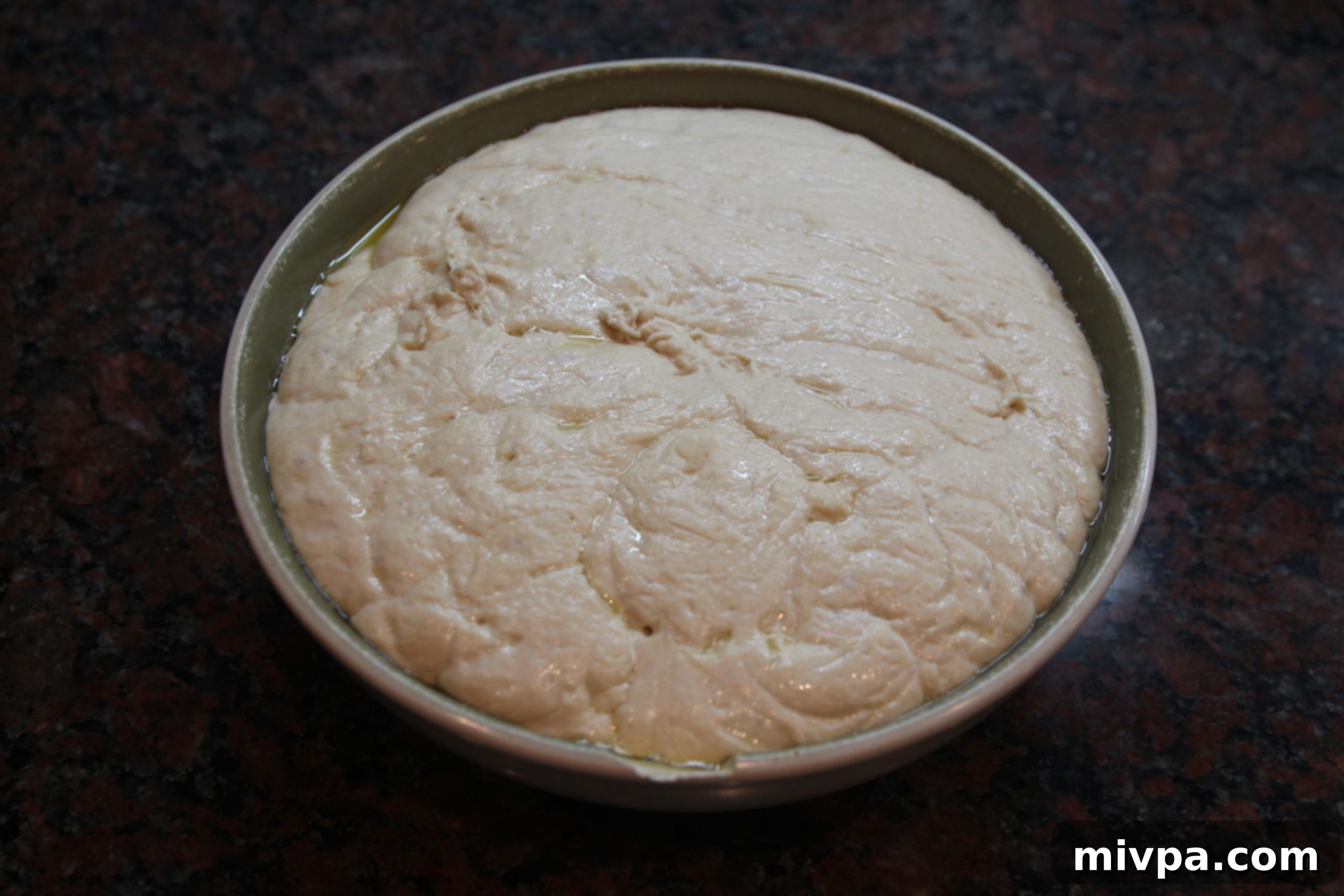 Ciabatta dough nearly doubled in size after the first rise in a bowl