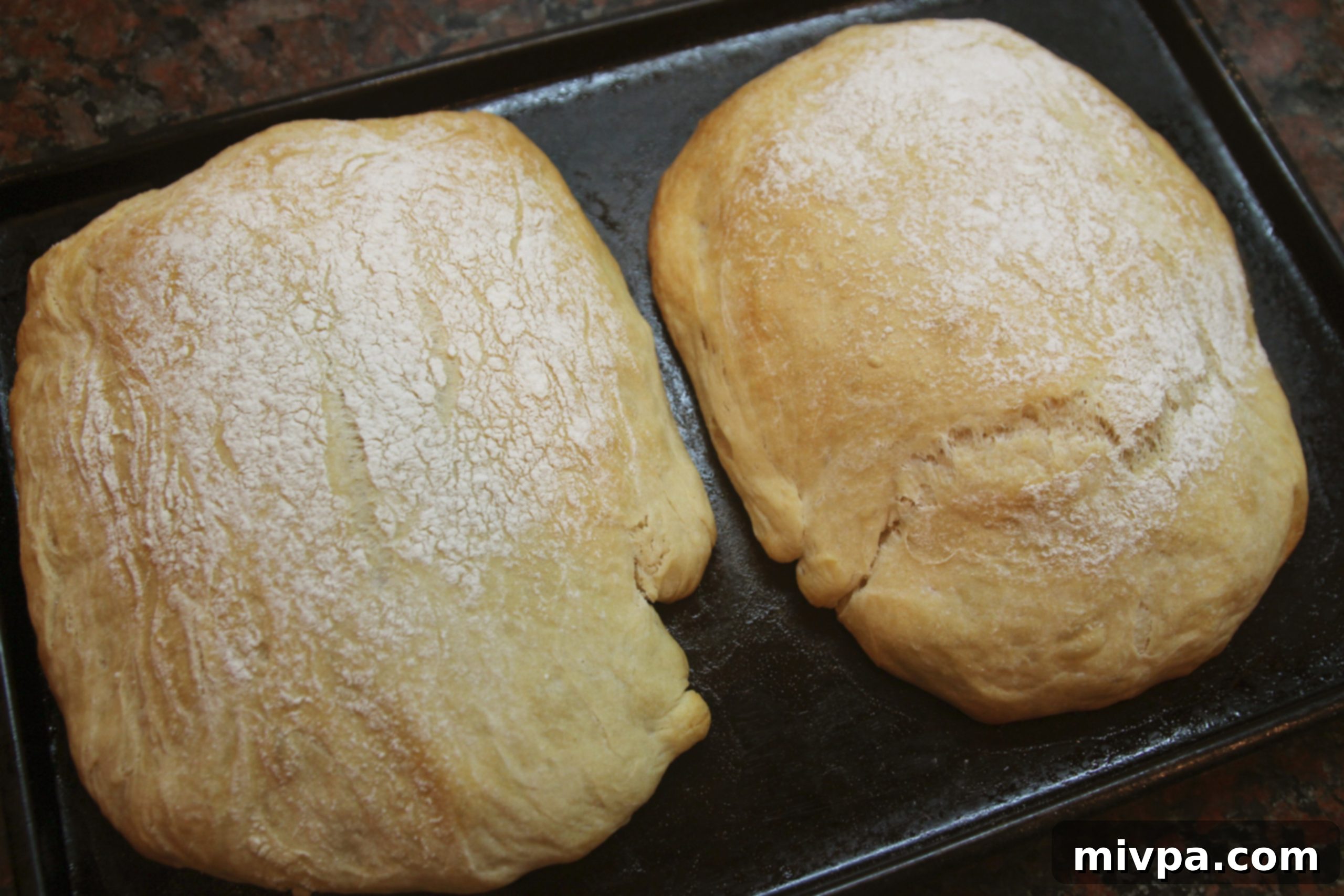 A freshly baked, golden-brown ciabatta loaf cooling on a wire rack