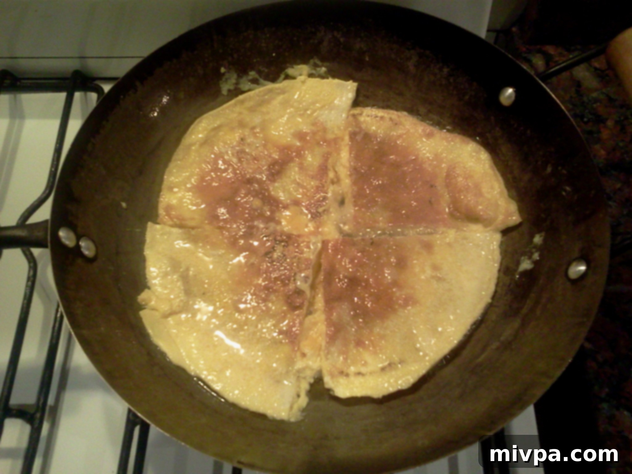 A thin omelette cooking in a pan, soon to be sliced and added to the fried rice.
