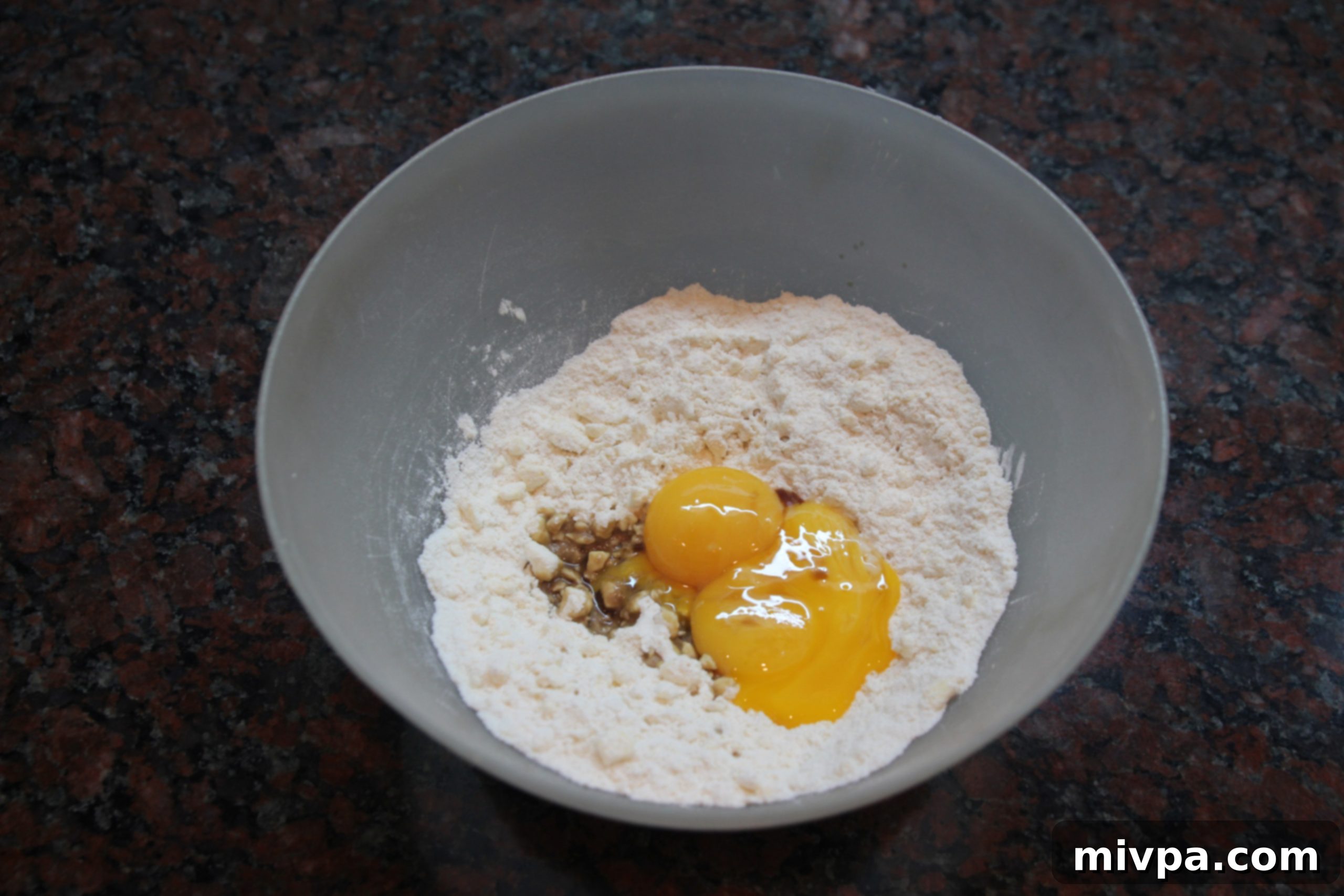 Adding rich egg yolks and aromatic vanilla extract to the prepared pastry mixture in a bowl.