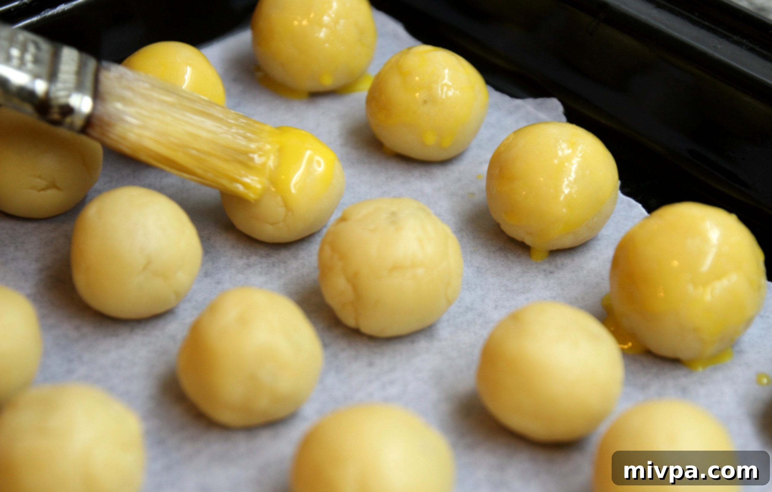 Brushing pineapple tarts with egg yolk glaze