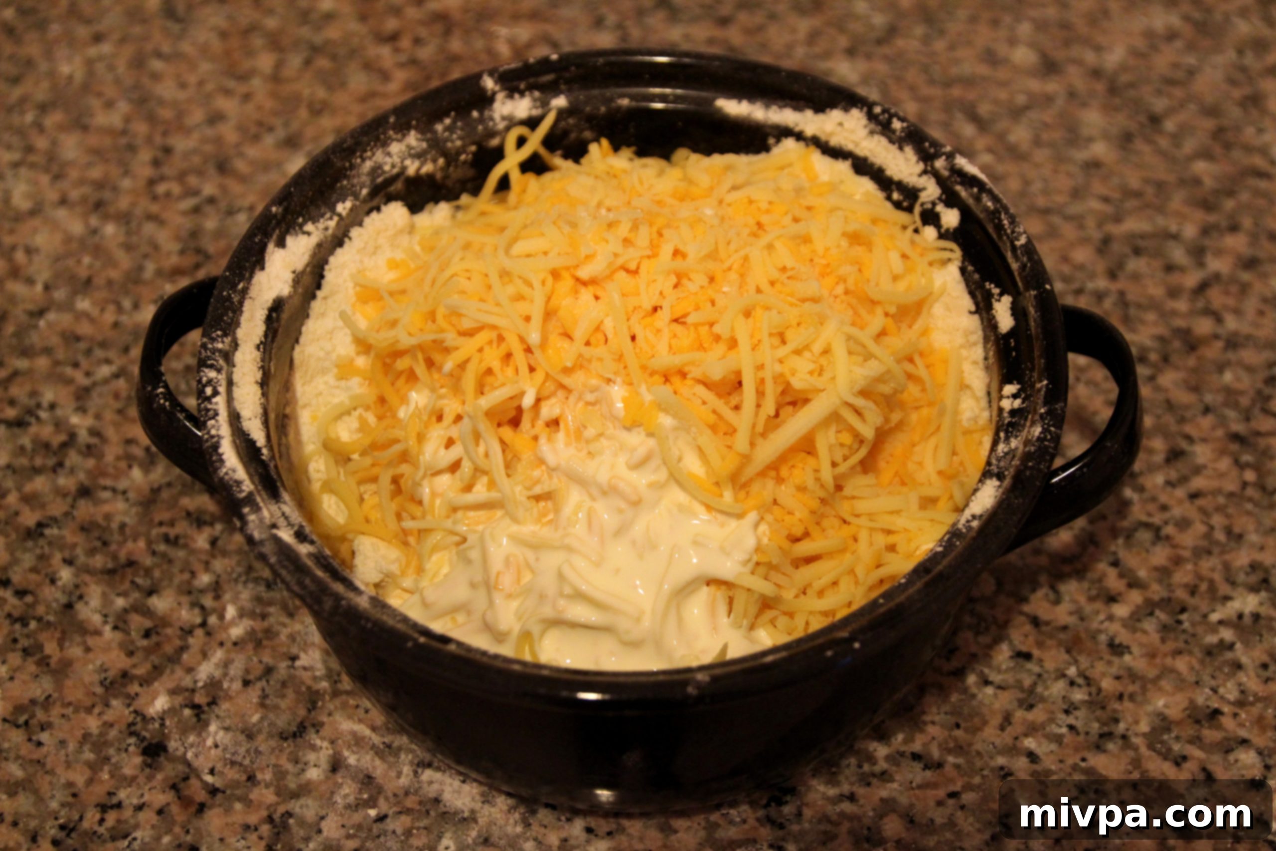 Adding cheese, cream, and milk to scone dough