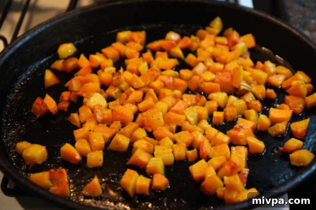 Butternut squash cubes seasoned and arranged on a baking tray, ready for roasting