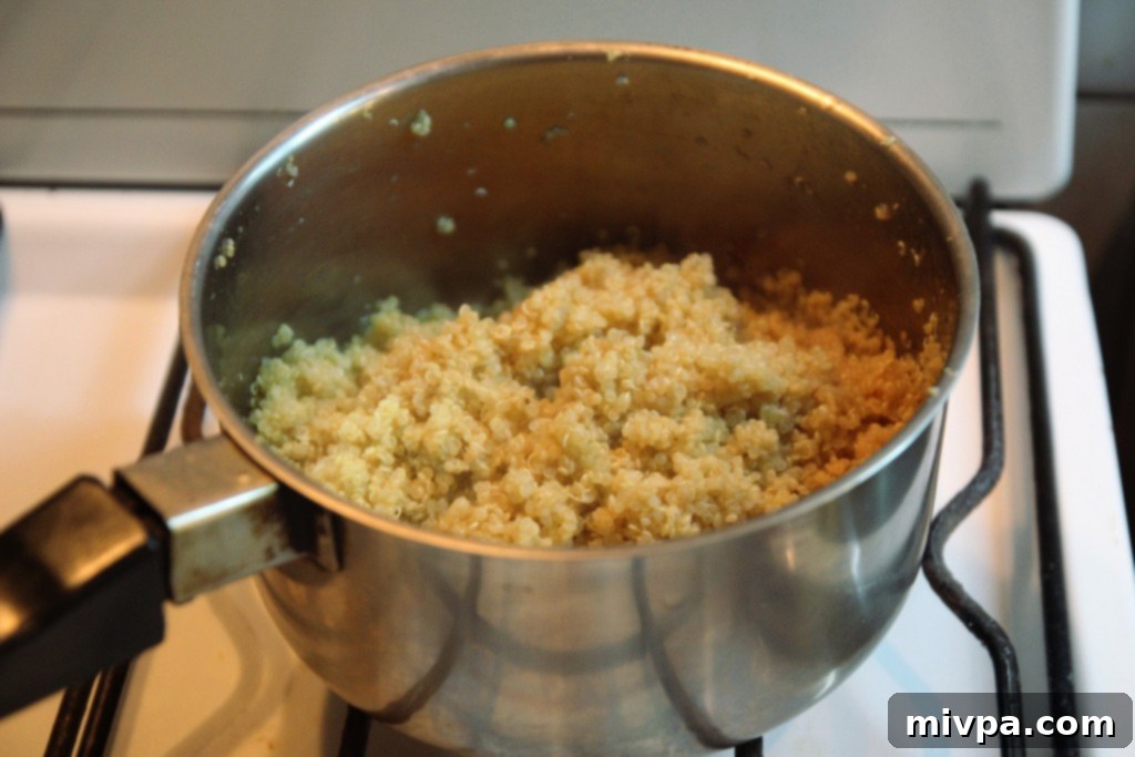 Cooked quinoa fluffed with a fork in a pot after absorbing water