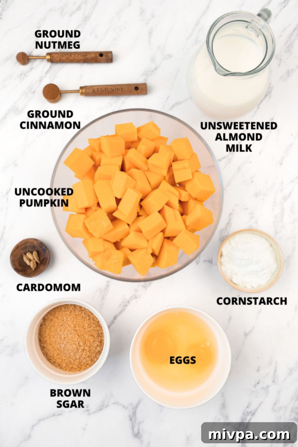 Creamy Pumpkin Pudding Recipe (Gluten-Free, Dairy-Free) Ingredients for gluten-free pumpkin pudding recipe laid out on a marble board, including pumpkin, milk, sugar, spices, and eggs.
