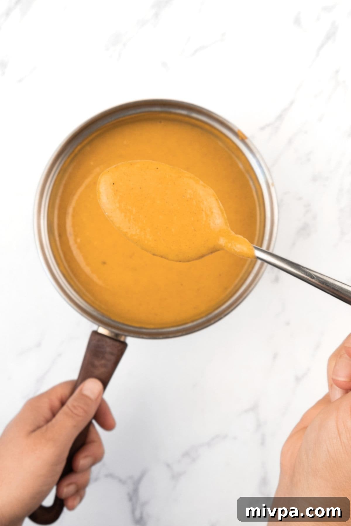 Easy Pumpkin Pie Pudding (Gluten-Free, Dairy-Free) Holding up a spoonful of the pumpkin mixture, showing its consistency before cooking.