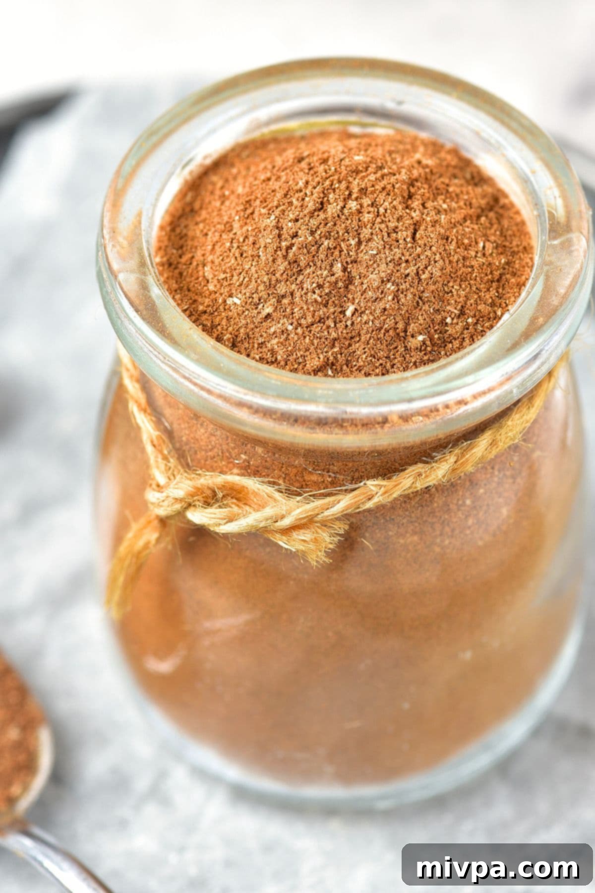 Homemade Apple Pie Spice (Gluten-Free, Vegan) Up close view of a jar of apple pie spice blend, highlighting its vibrant color and fresh aroma.