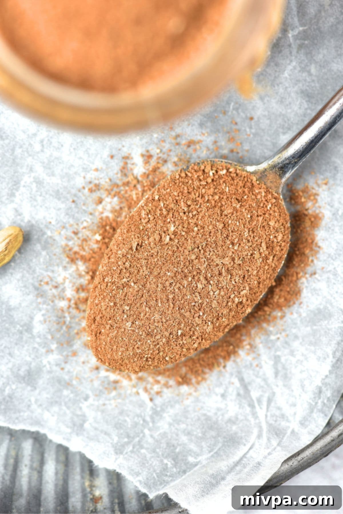 How to Make Apple Pie Spice Mix at Home A close-up of a spoonful of rich, aromatic apple pie spice mix, showcasing its fine texture.