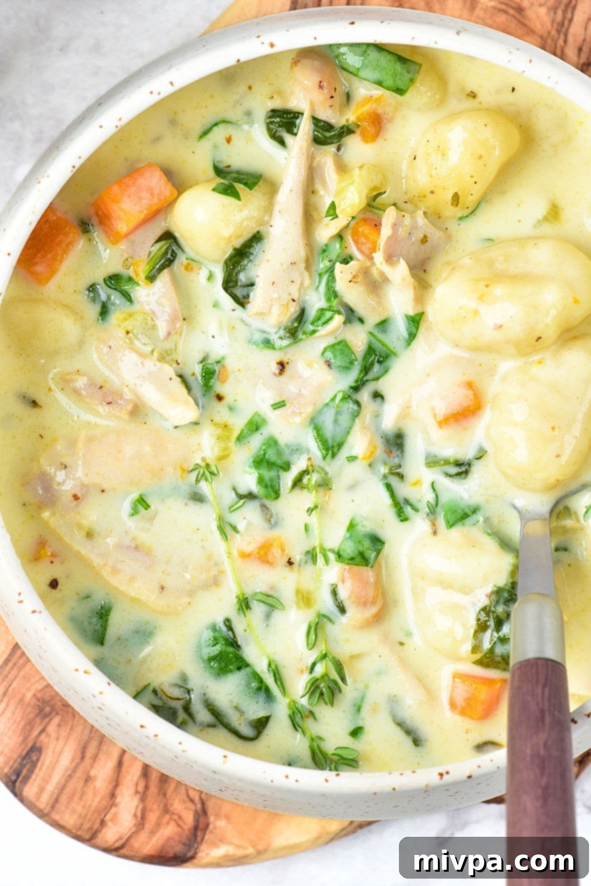 Creamy Gluten-Free Dairy-Free Chicken Gnocchi Soup Top down view of a bowl of creamy chicken gnocchi soup, garnished with fresh herbs and a swirl of cream.