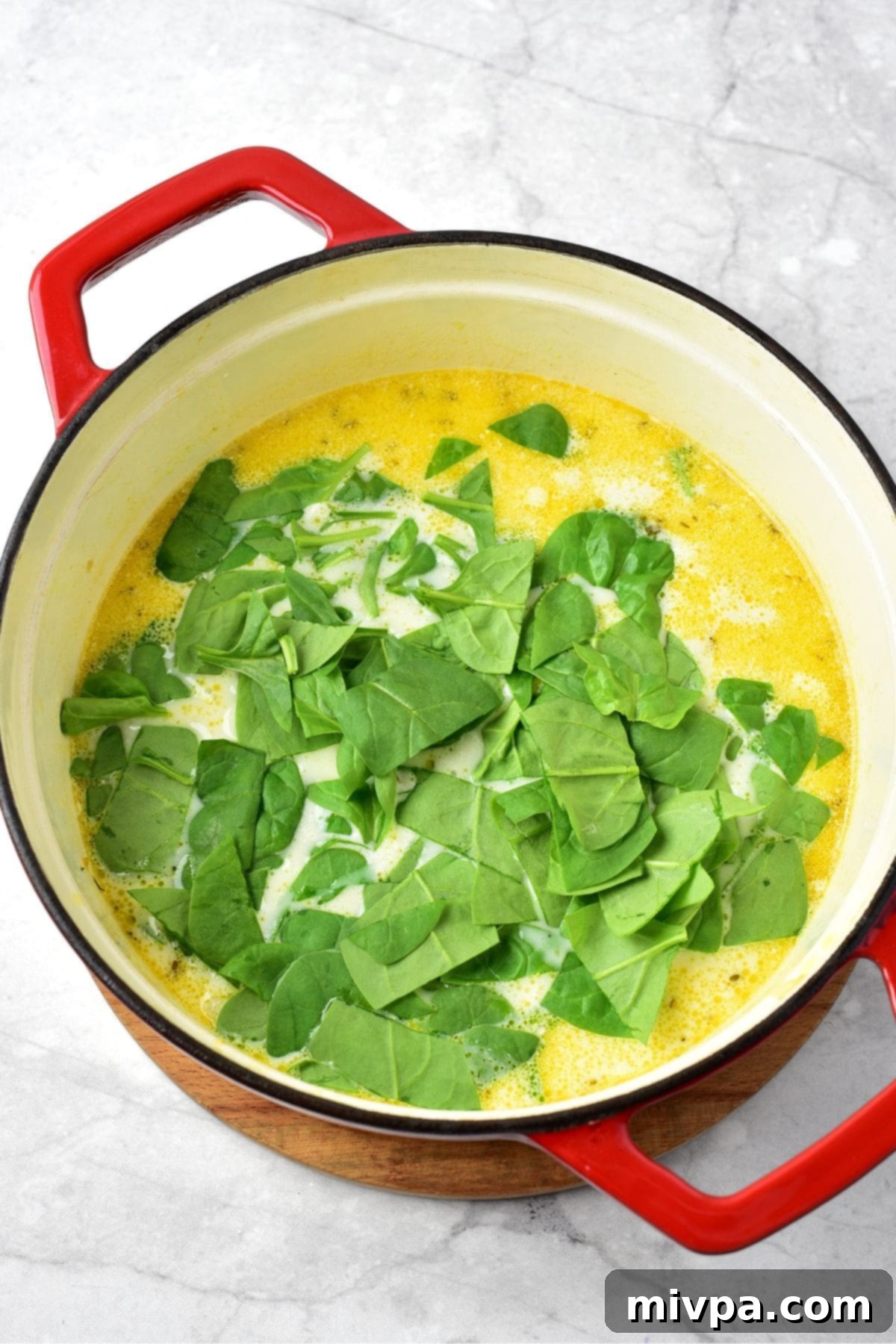 Gluten-Free Dairy-Free Creamy Chicken Gnocchi Soup 2 Fresh green spinach leaves added on top of the creamy soup in the pot, beginning to wilt.