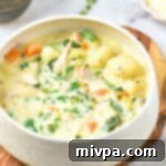 Gluten-Free Dairy-Free Creamy Chicken Gnocchi Soup 4 A bowl of creamy gluten-free chicken gnocchi soup on a wooden board, garnished with fresh herbs.