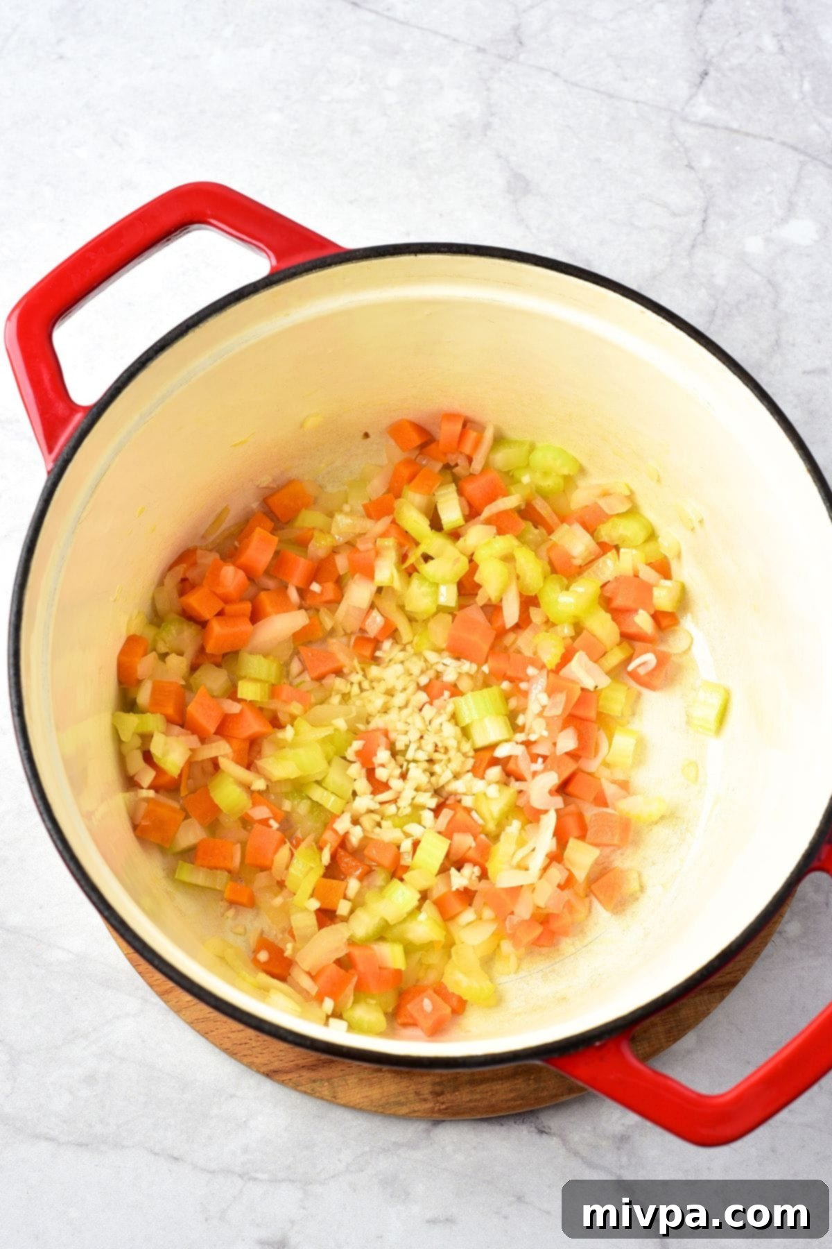 Sautéing Vegetables for Gnocchi and Chicken Soup Cubed carrots, celery, onions, and minced garlic sautéing in olive oil in a large Dutch oven until softened.