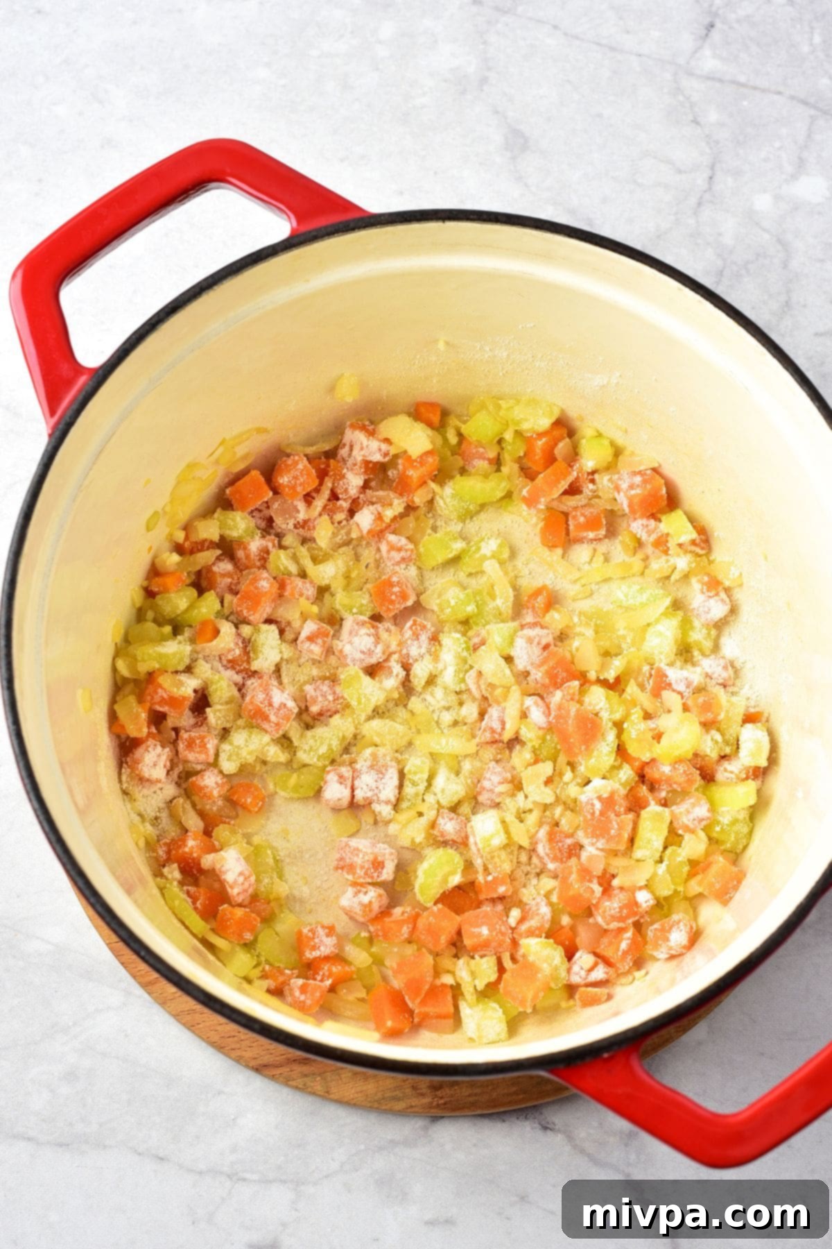 Adding Flour for Creamy Chicken Gnocchi Soup Gluten-free flour sprinkled evenly over the sautéed vegetables in the pot, being stirred to form a roux.