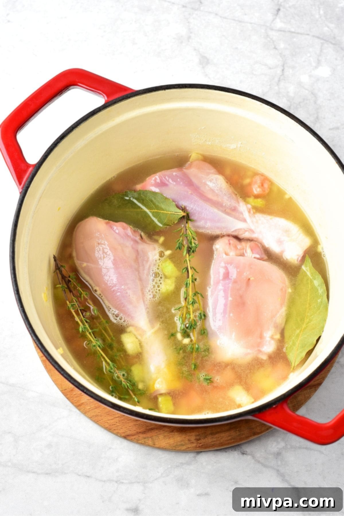 Cooking Chicken and Broth for Gnocchi Chicken Soup Chicken drumsticks, bay leaves, thyme, and chicken broth added to the sautéed vegetables in the Dutch oven, simmering gently.