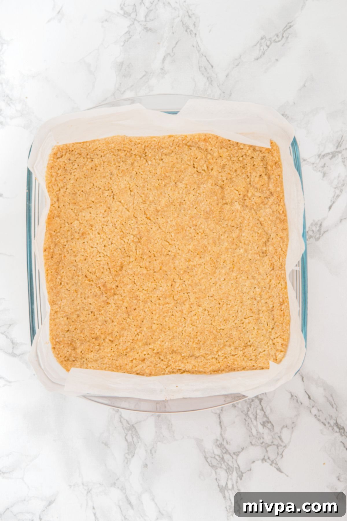 Wholesome Gluten-Free Vegan Apple Oat Bars 2 The baked, lightly golden crust cooling in its parchment-lined glass pan after its initial bake.