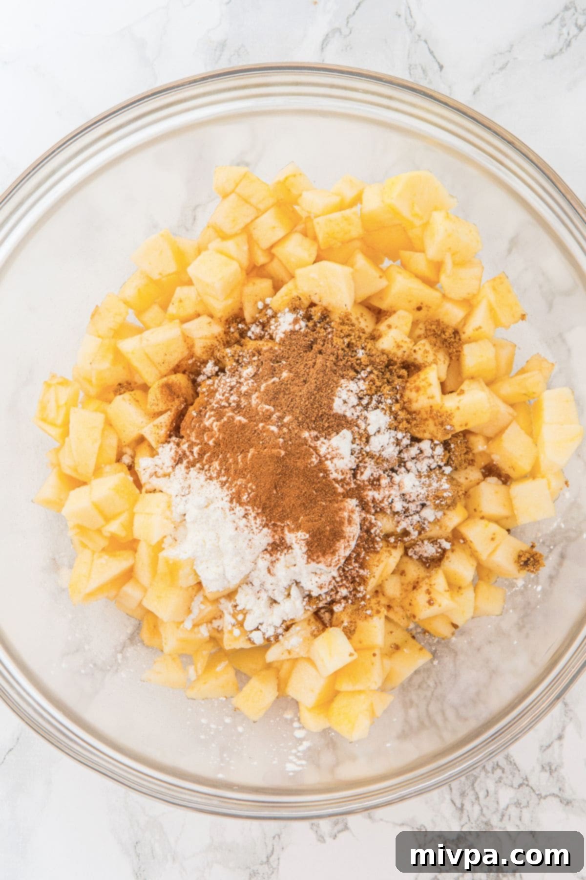 Wholesome Gluten-Free Vegan Apple Oat Bars 3 Diced apples tossed with cornstarch, brown sugar, ground cinnamon, and ground nutmeg in a bowl, forming the flavorful apple filling.