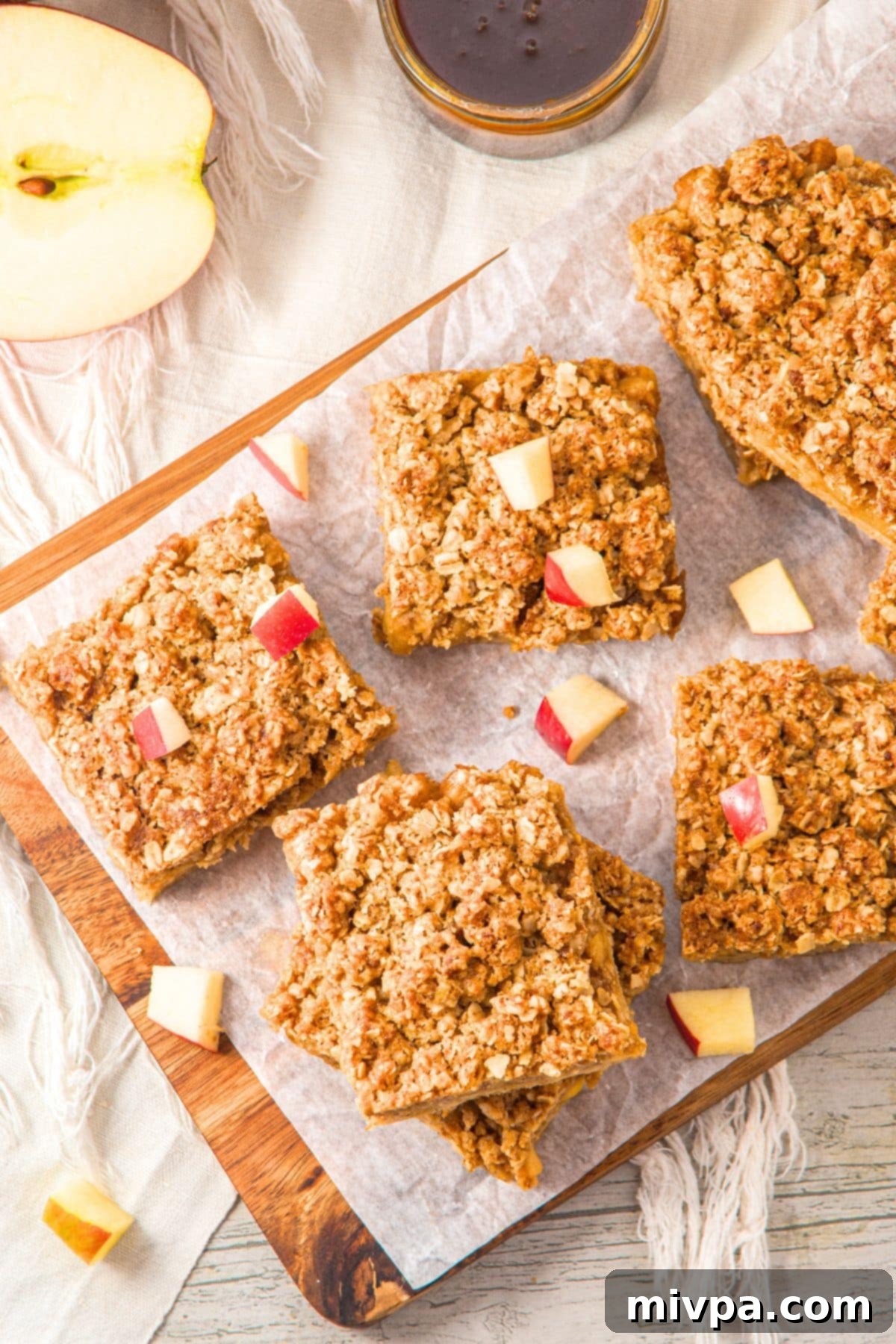 Apple and Oatmeal Bars Recipe A top-down view of the freshly baked apple oatmeal bars, golden and tempting, on parchment paper after cooling slightly, awaiting slicing.