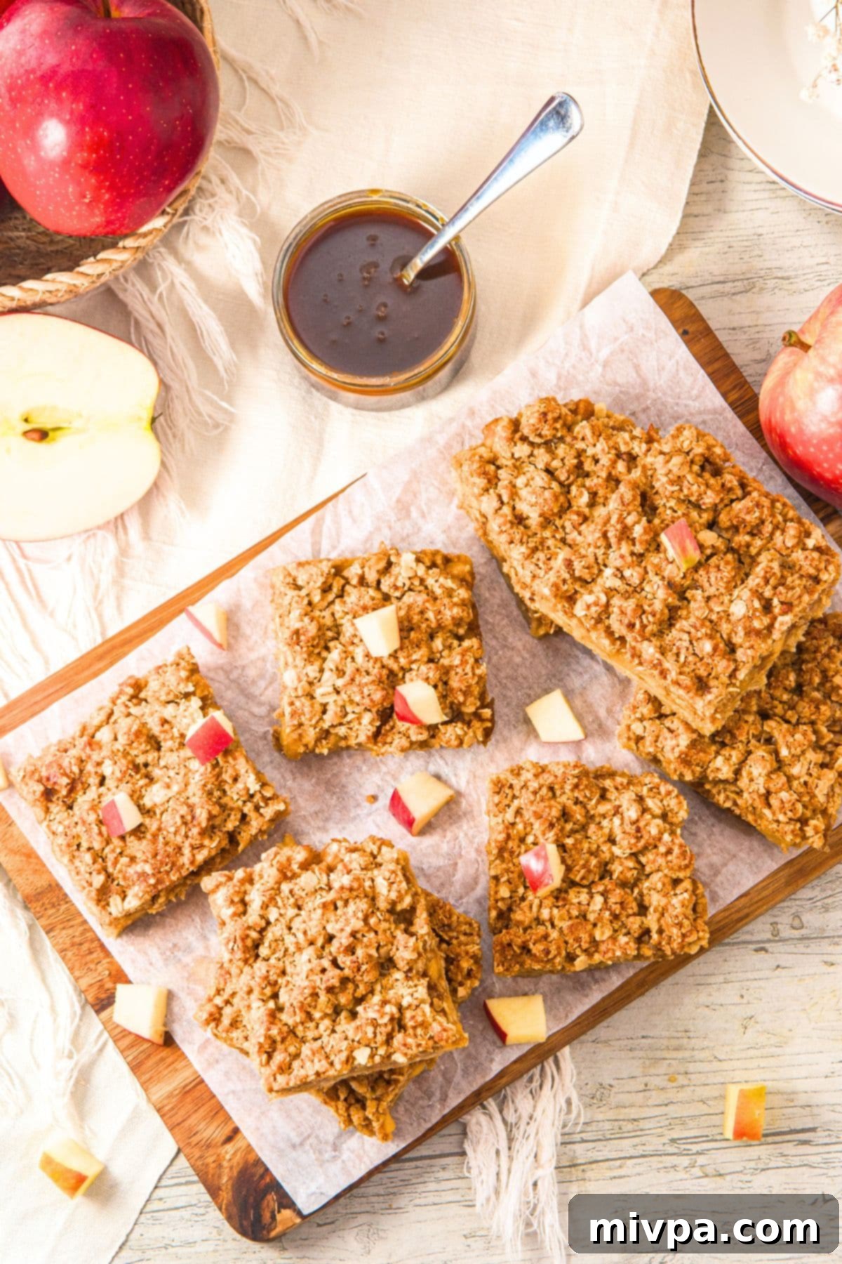 Oatmeal Apple Bars (Gluten-Free, Vegan) Top down view of freshly baked apple oatmeal bars neatly arranged on parchment paper, ready to be cut.