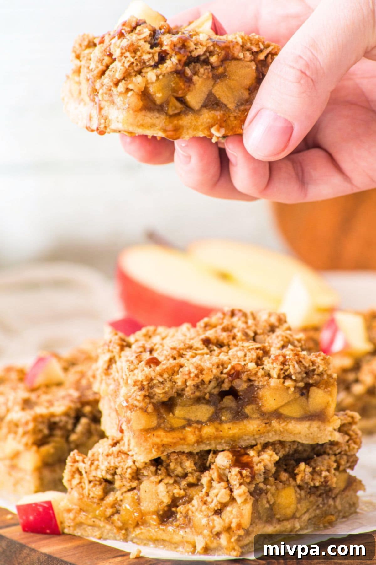 Apple Oat Bars (Gluten-Free, Vegan) A hand holding up a single apple oatmeal bar, showing its distinct layers and appealing texture.