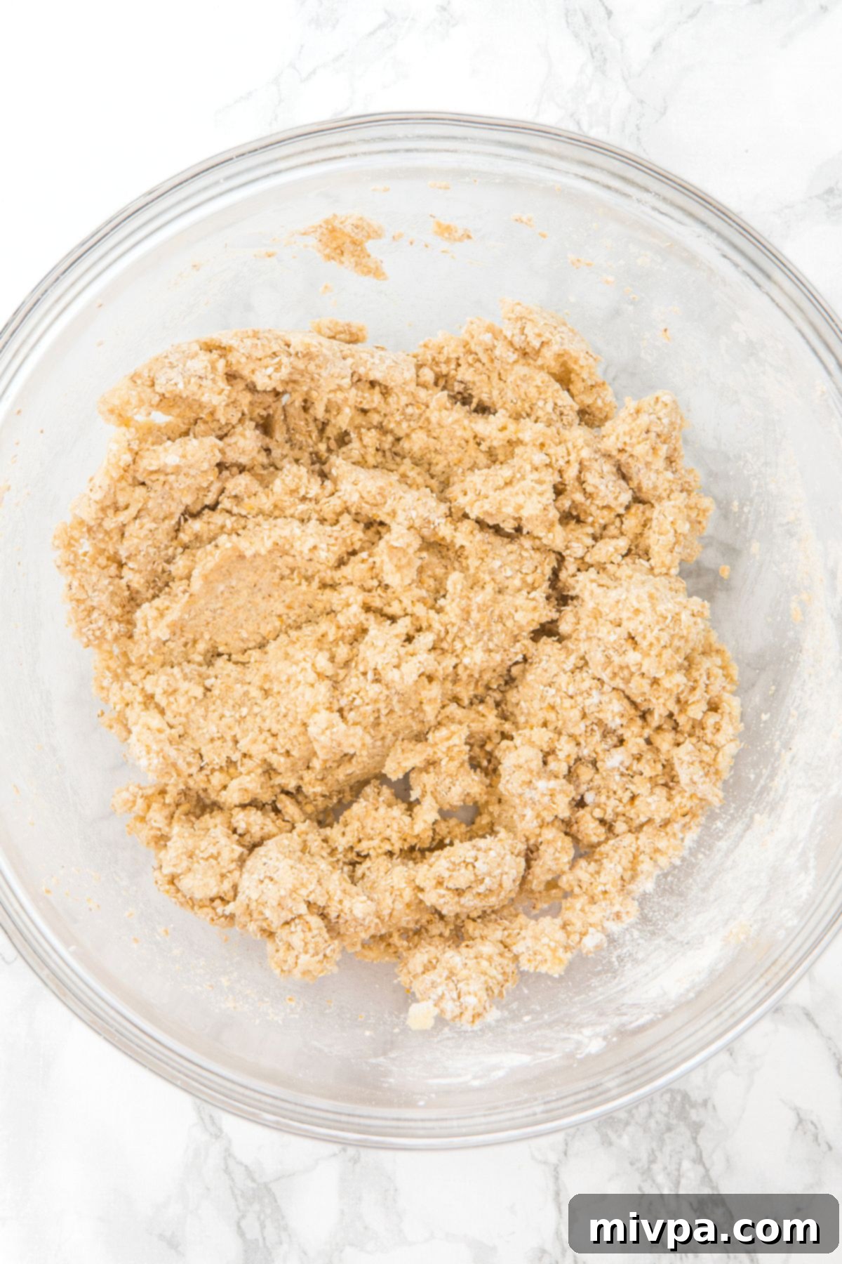 Gluten-Free Vegan Apple Oatmeal Bars A glass bowl containing the homogeneous crust mixture, combining creamed butter with oat flour, cornstarch, and salt.