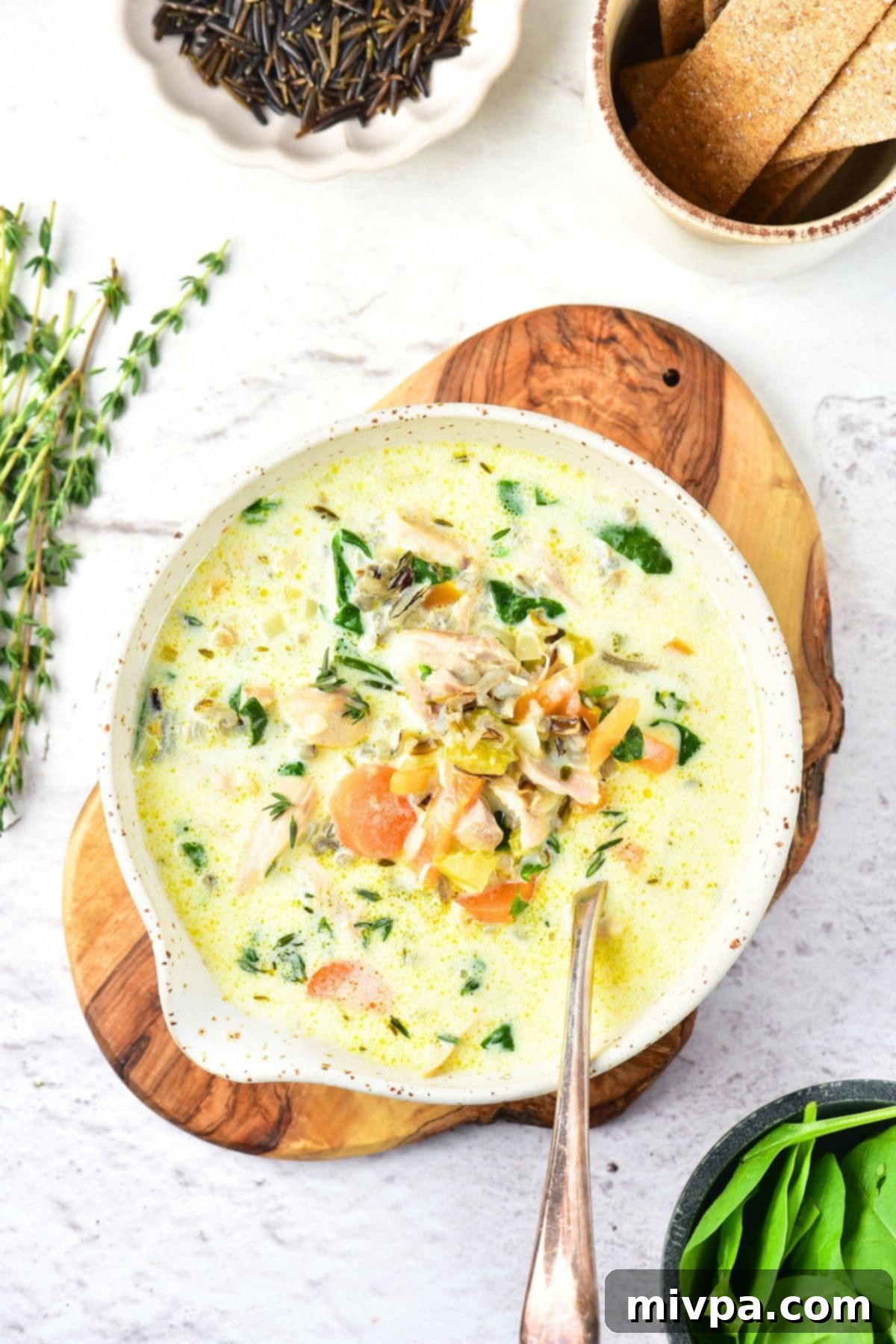 Creamy Chicken and Wild Rice Soup Recipe (Gluten-Free, Dairy-Free) A spoon in a bowl of beautifully garnished chicken and wild rice soup, ready to enjoy.