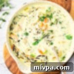 Creamy Chicken Wild Rice Soup Gluten Free Dairy Free 2 A bowl of chicken and wild rice soup on wooden board.