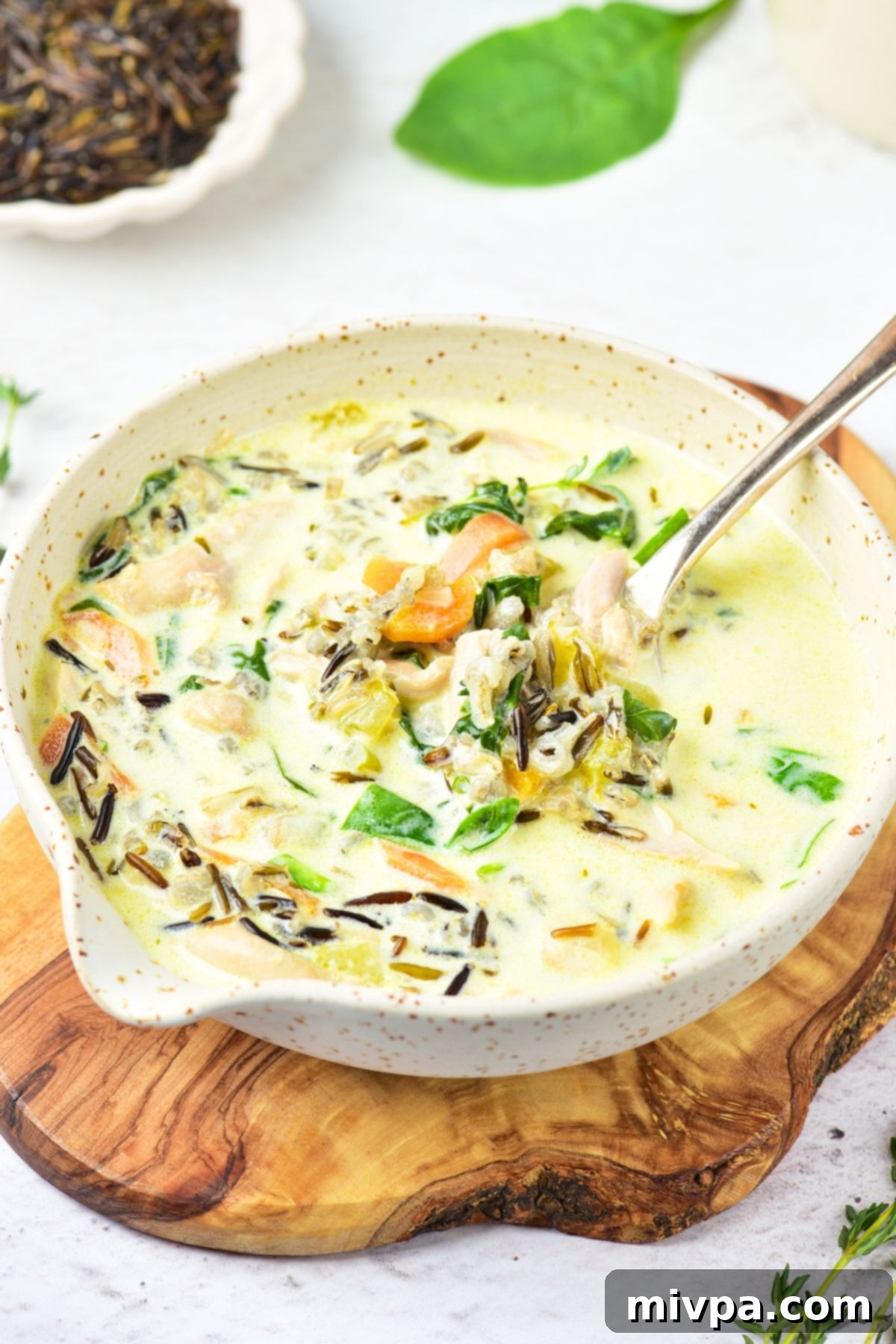 Creamy Chicken Wild Rice Soup (Gluten-Free, Dairy-Free) Holding up a spoonful of creamy chicken wild rice soup, showcasing its rich texture and ingredients.