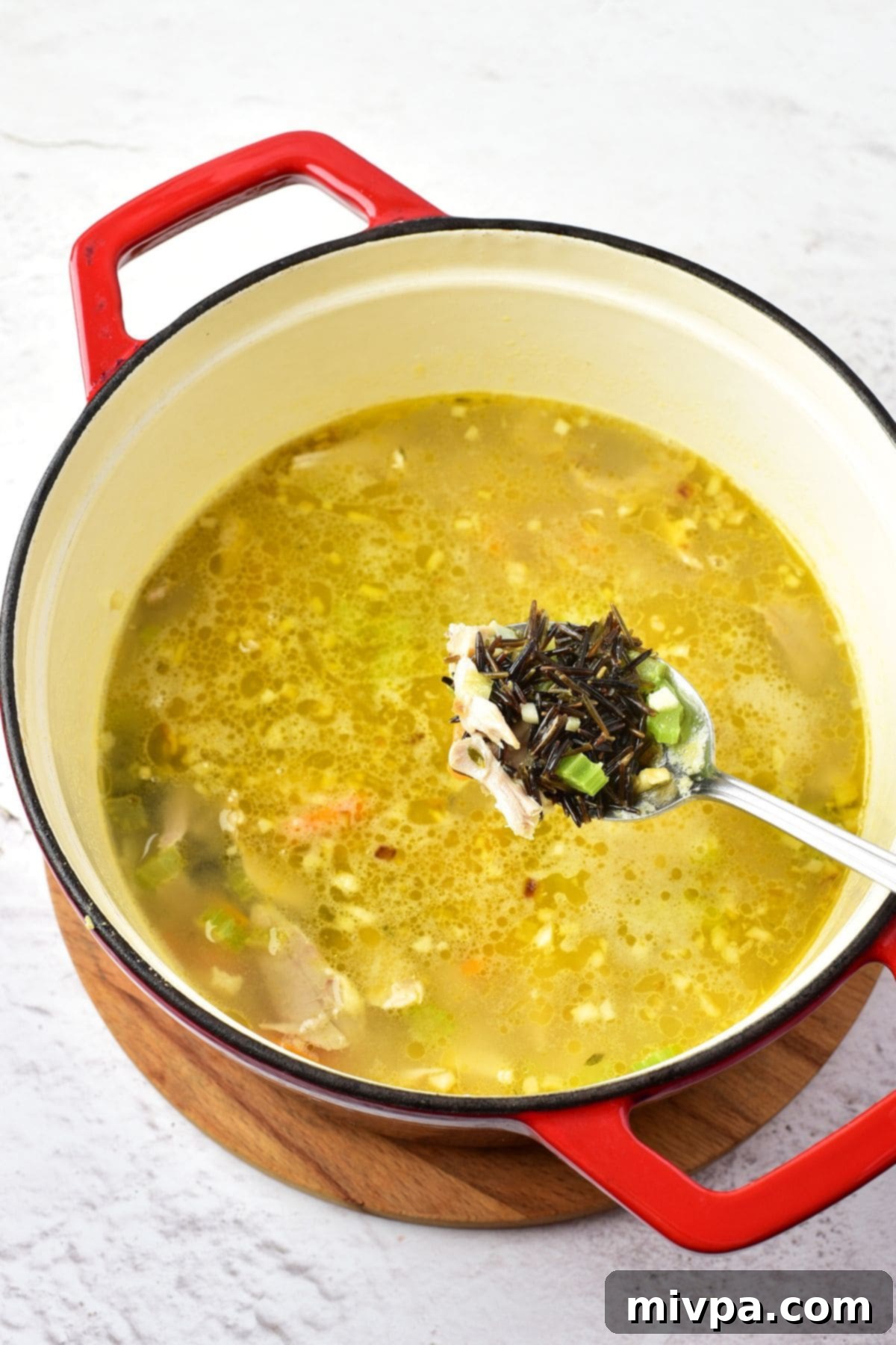 Wild Rice and Chicken Soup Adding wild rice, broth, chicken, and seasonings to the soup pot, ready for simmering.