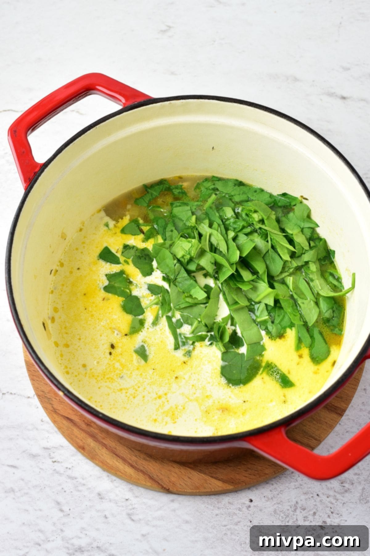 Chicken Wild Rice Creamy Soup Sliced spinach being stirred into a pot of creamy chicken wild rice soup.