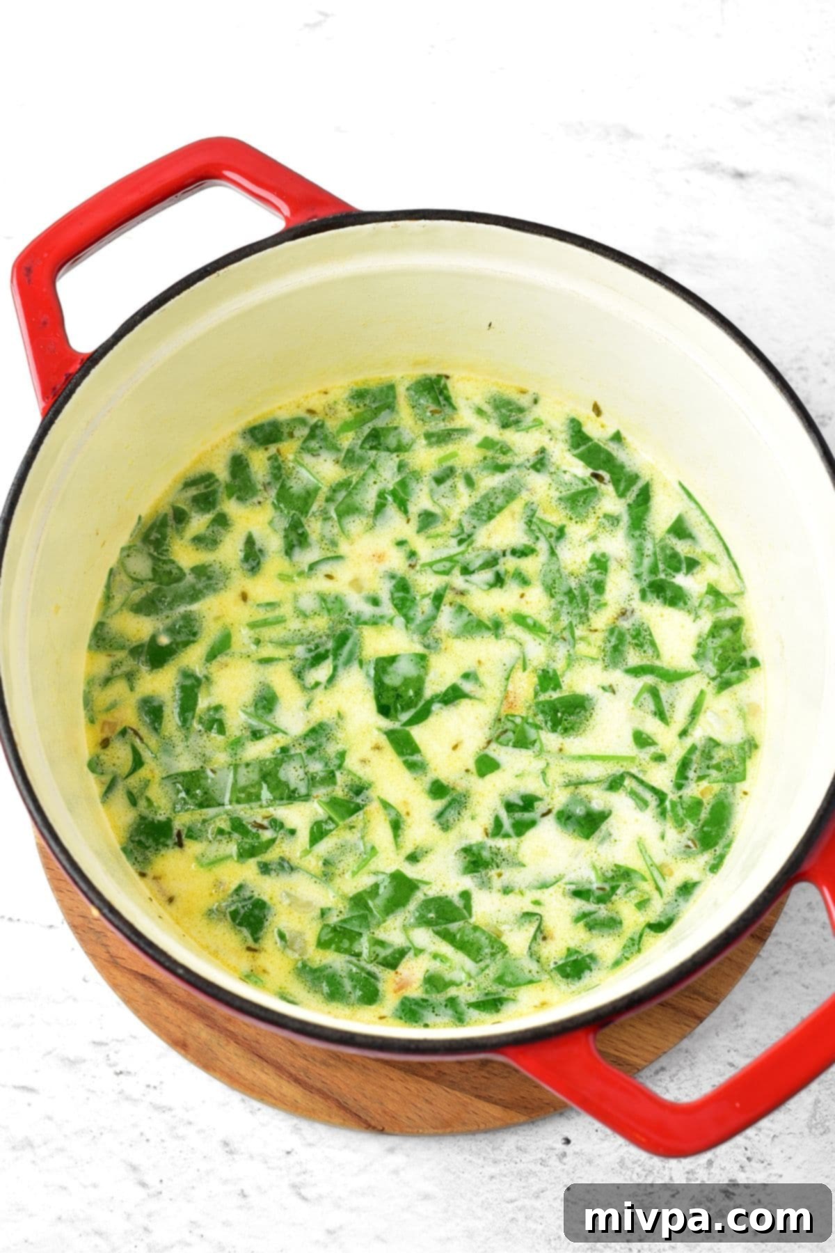 Gluten Dairy-Free Chicken Wild Rice Soup Cooked spinach in a pot of chicken and wild rice soup, ready to be served after resting.