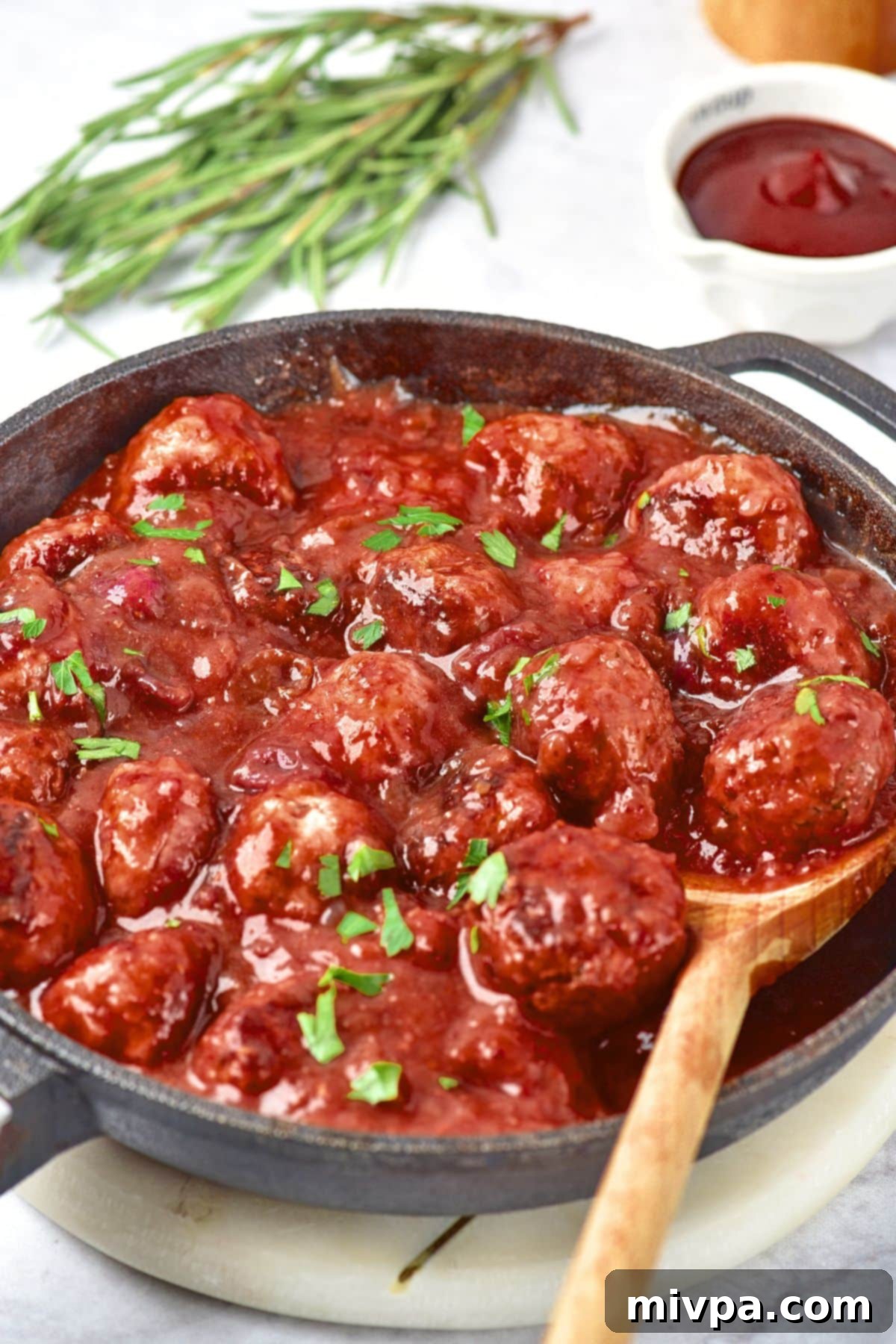 Cranberry Meatballs (Gluten-Free, Dairy-Free) A wooden spoon in skillet with cranberry meatballs