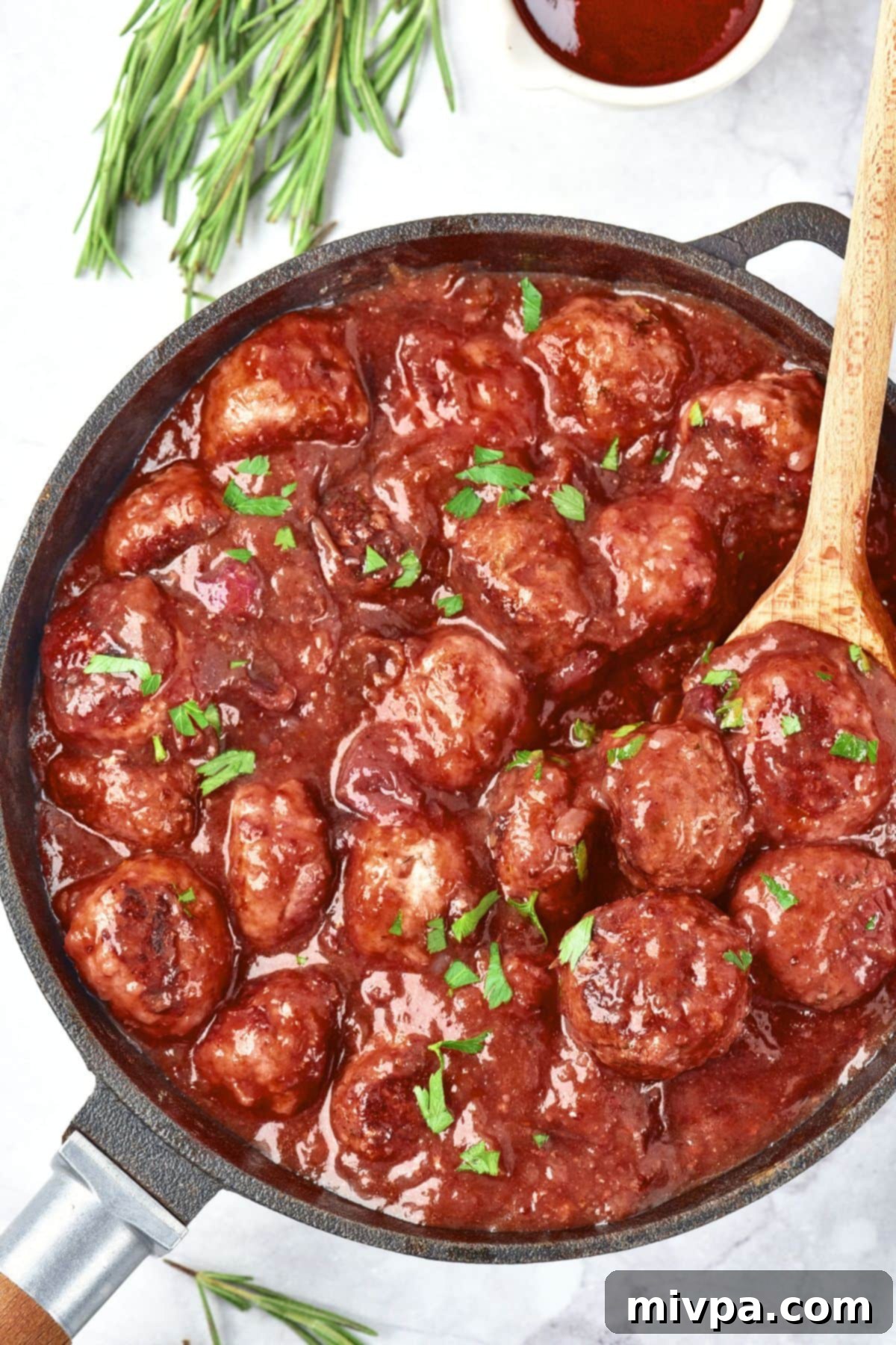 Slow Cooker Cranberry Meatballs (Gluten-Free, Dairy-Free) Spooning a meatball from a skillet