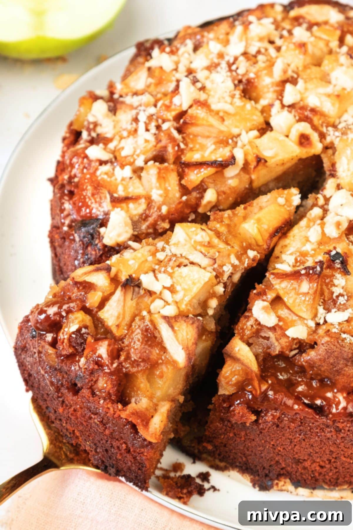 Gluten-Free Swedish Apple Cake (Äppelkaka) with Caramel and Nuts Half-eaten slice of Swedish apple cake showing tender crumb and apple topping with caramel.