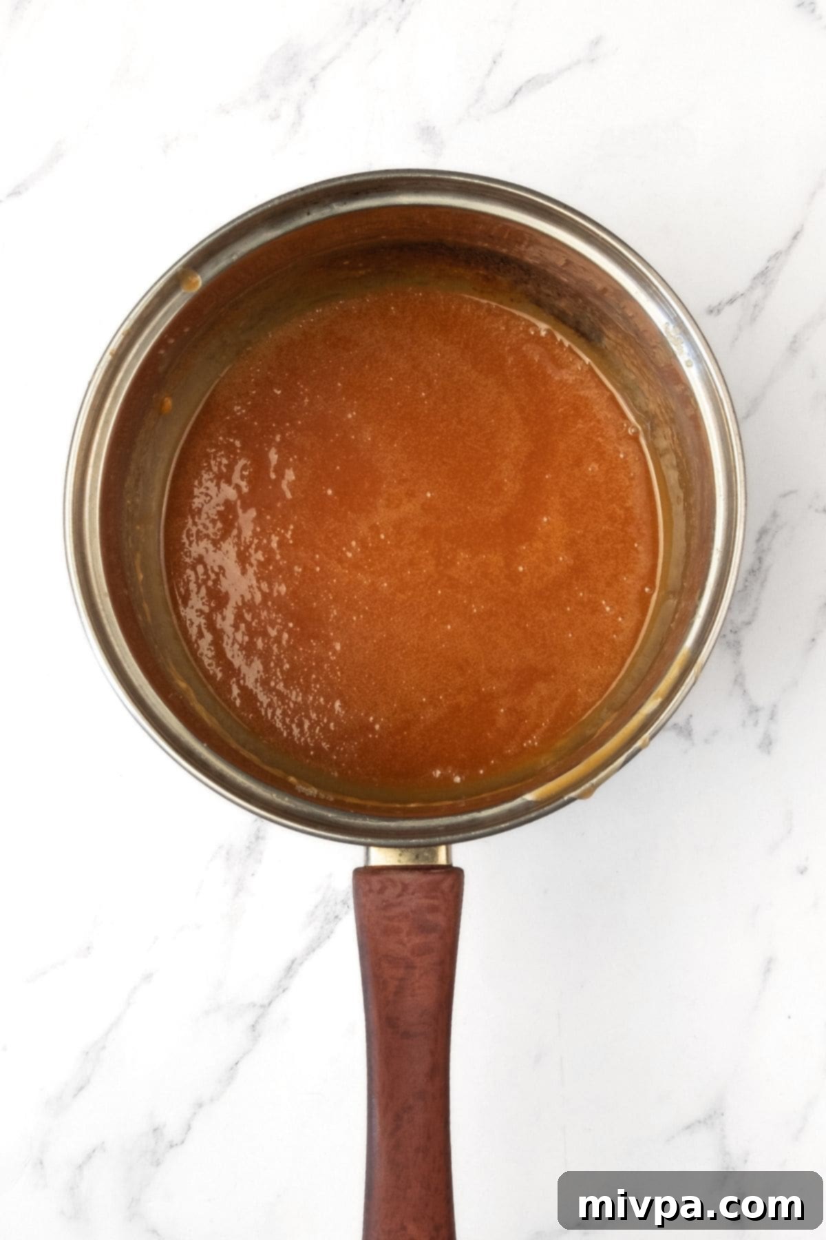 Homemade Caramel for Gluten-Free Apple Swedish Cake Golden brown caramel sauce bubbling gently in a small saucepan.