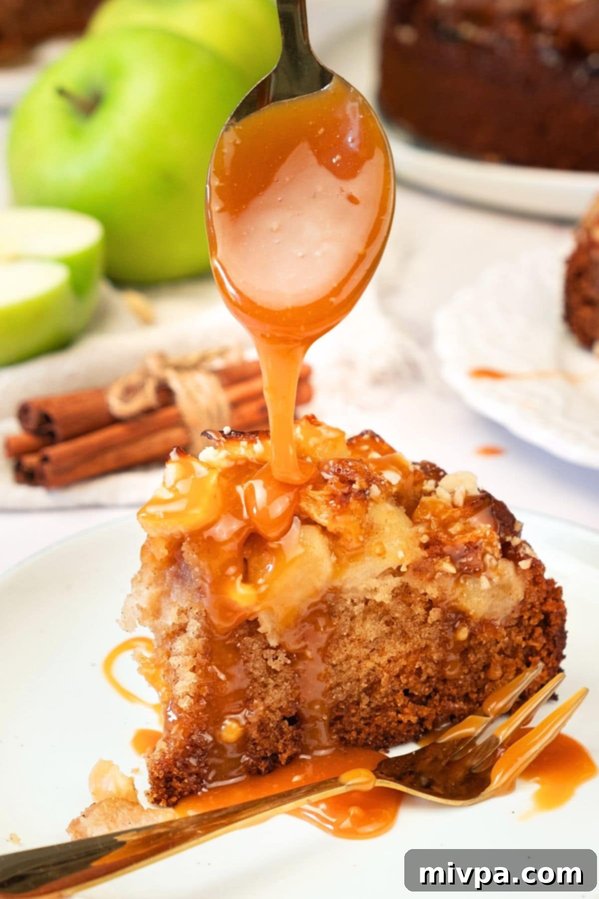 Caramel Drizzle on Apple Swedish Cake (Gluten-Free, Dairy-Free Option) A hand drizzling golden caramel sauce over a slice of apple Swedish cake on a serving plate.