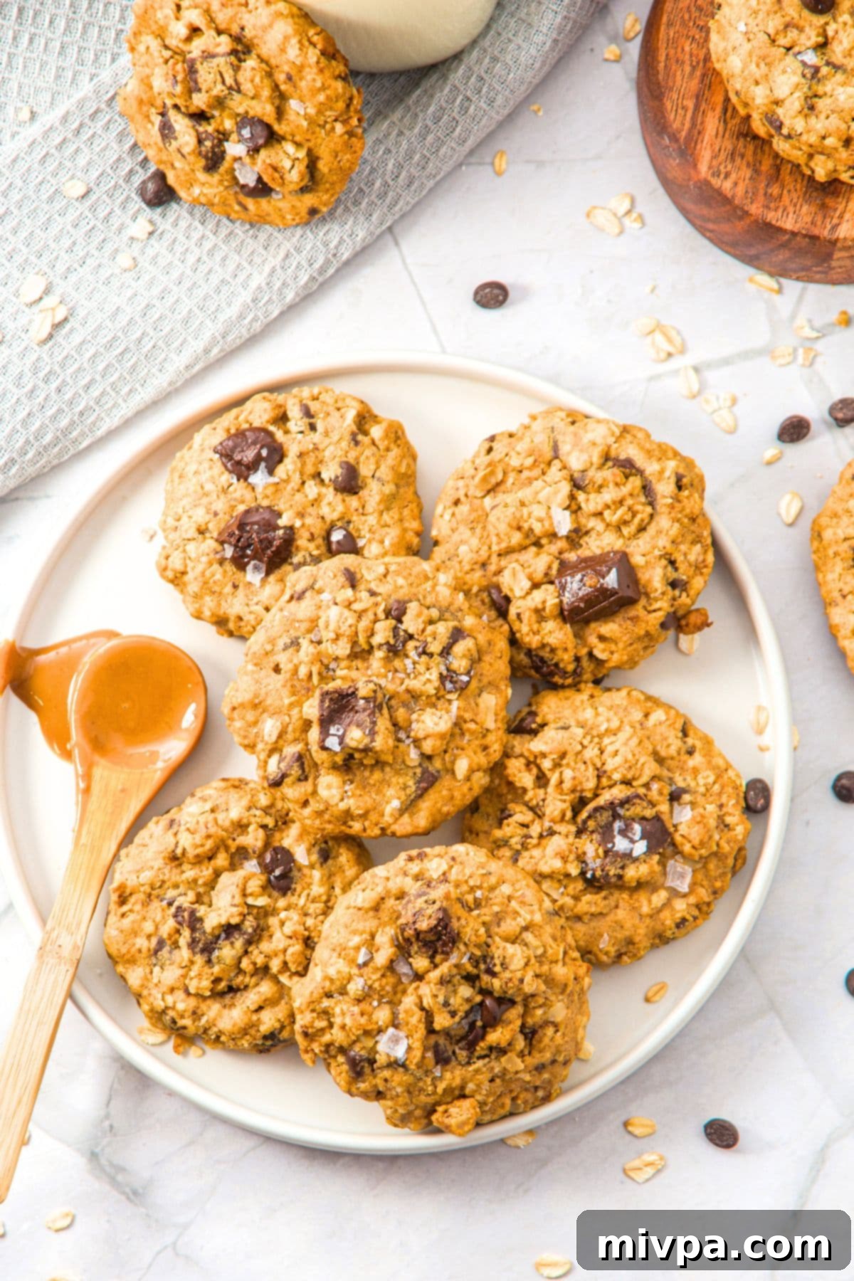 Top down view of plate of peanut butter oatmeal cookies with chocolate chunks, some broken in half to show the soft interior.
