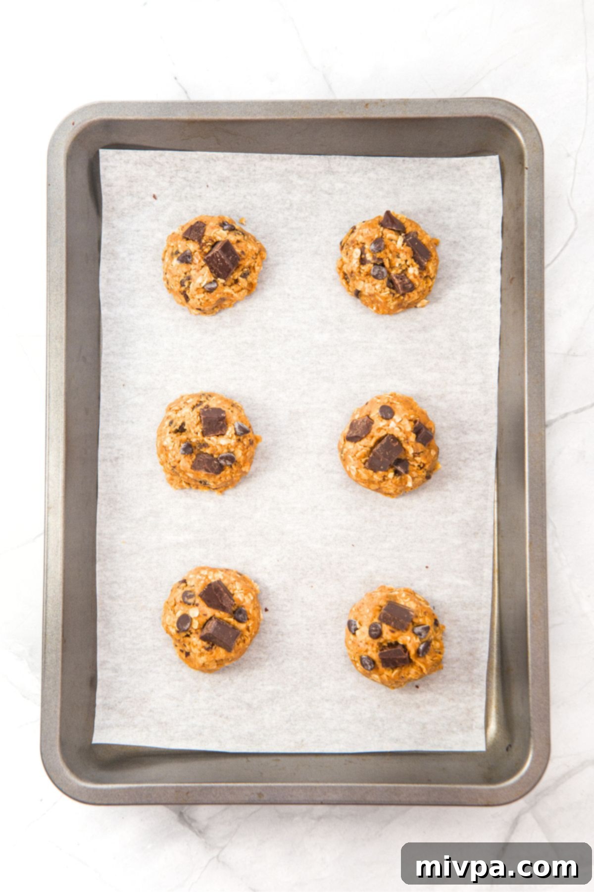 Evenly spaced cookie dough balls placed on a parchment-lined baking sheet, ready for the oven.