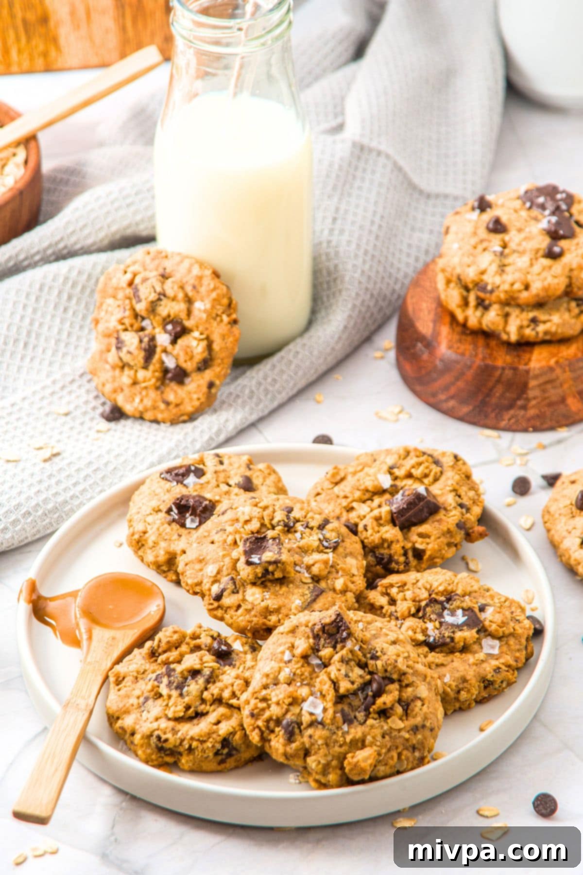 A plate filled with perfectly golden-brown peanut butter and oatmeal cookies, some with visible chocolate chips.