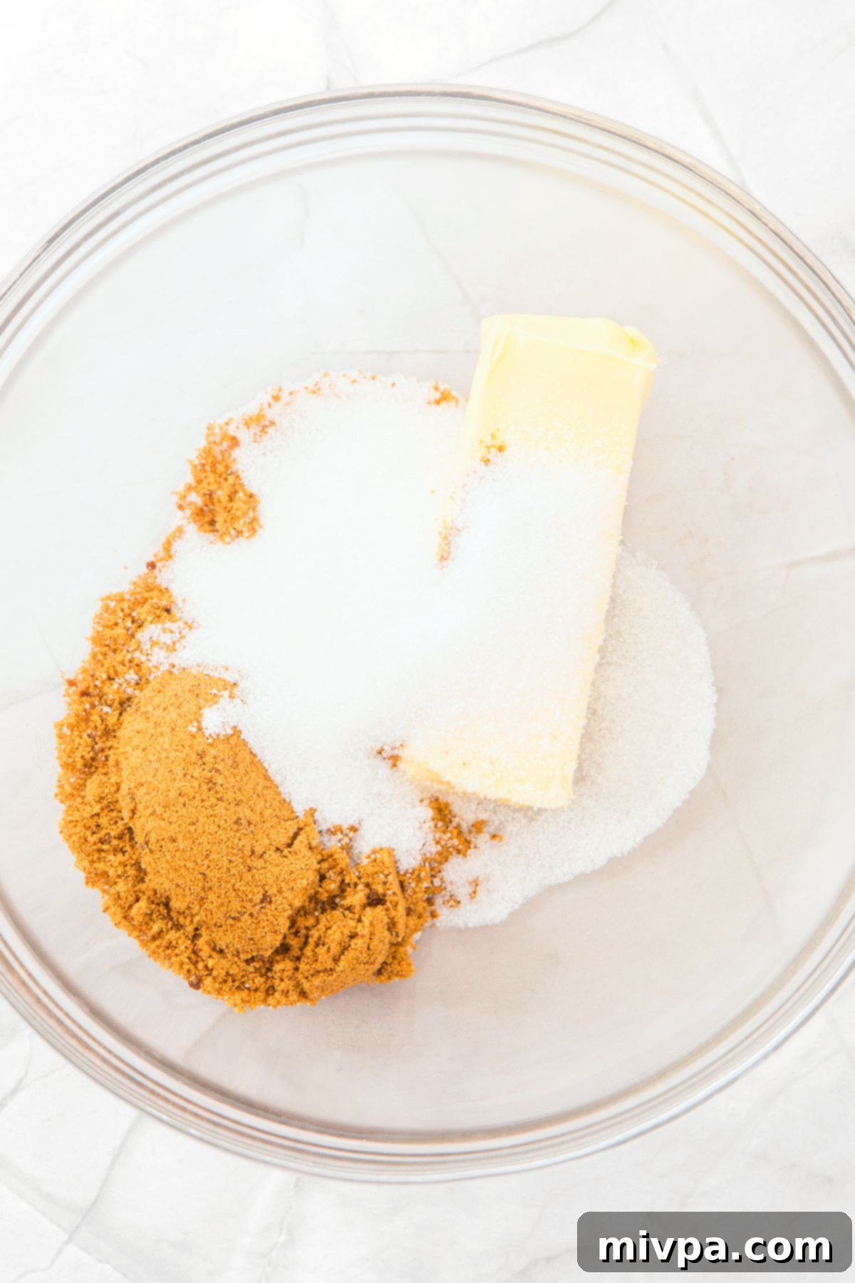 A bowl containing a creamy mixture of dairy-free butter, brown sugar, and white granulated sugar.