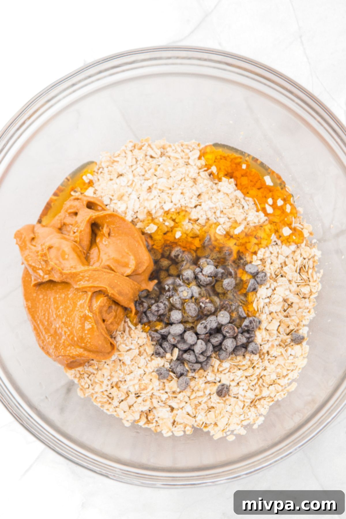 Peanut Butter and Oatmeal Balls (Gluten-Free, Vegan) Peanut butter, oats, chocolate chips and maple syrup in glass bowl