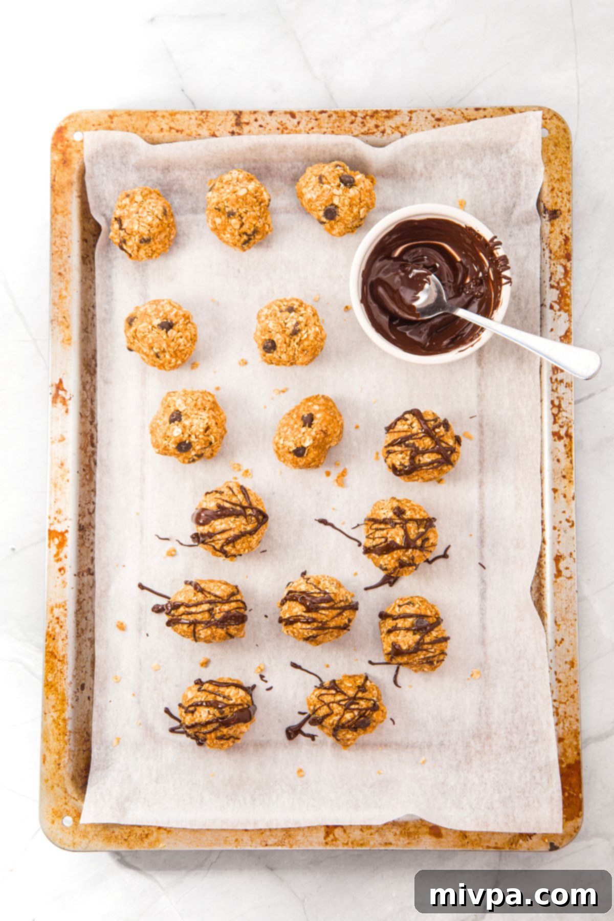 Oatmeal and Peanut Butter Energy Balls Chocolate drizzled oatmeal and peanut butter energy balls on baking sheet