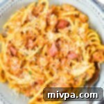 Luxurious Gluten and Dairy Free Pumpkin Carbonara 4 A bowl of creamy pumpkin carbonara sprinkled with shredded dairy-free cheese