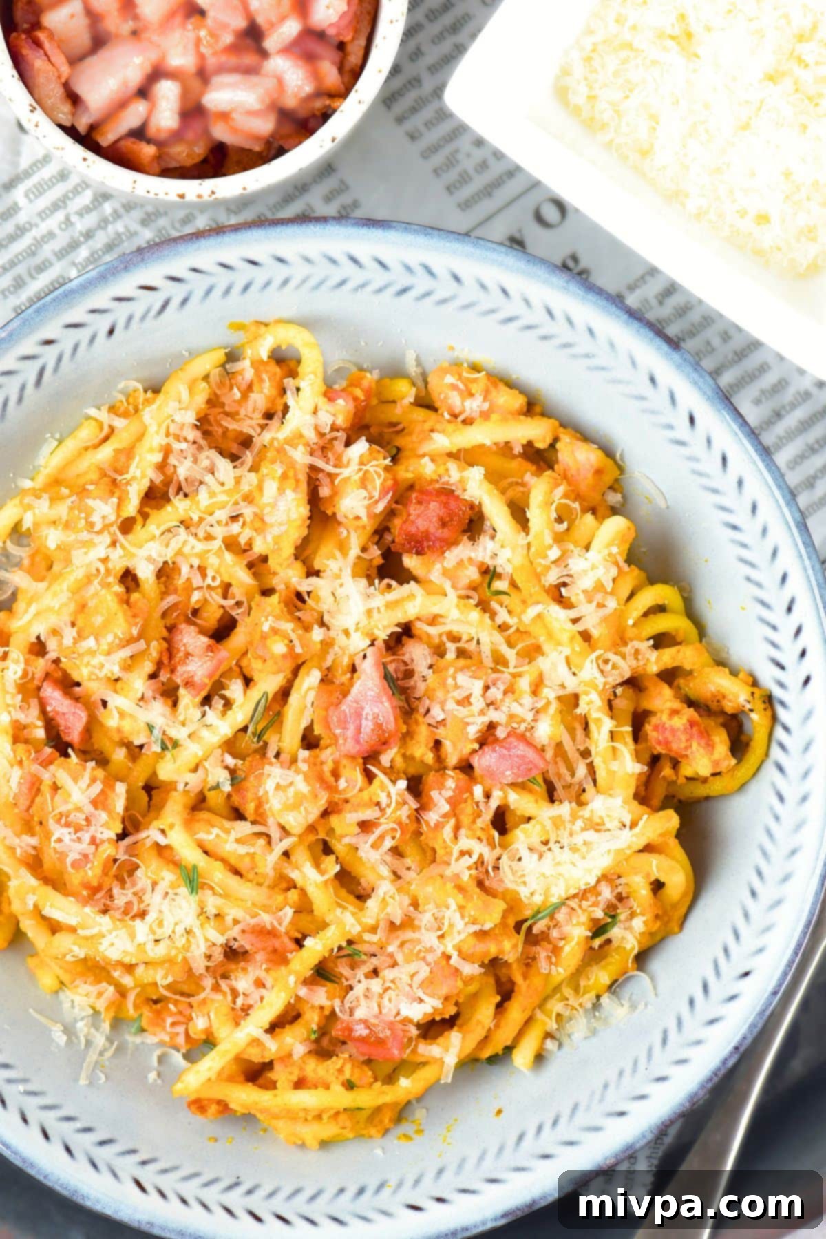 Pumpkin Spaghetti Carbonara (Gluten-Free, Dairy-Free Fall Recipe) Top down view of a plate of pumpkin spaghetti carbonara with shredded cheese and fresh herbs