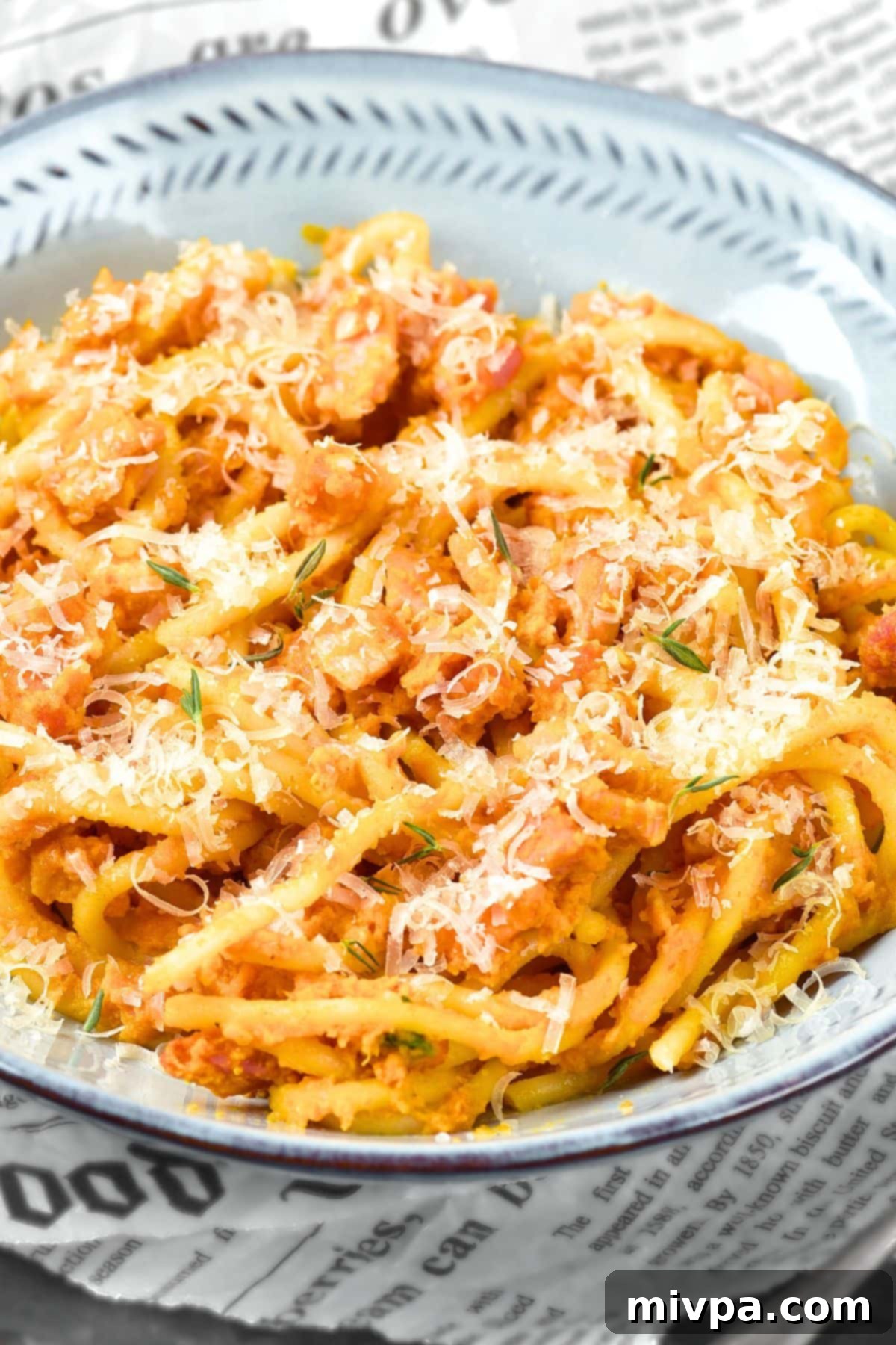 Gluten-Free Spaghetti Carbonara with Pumpkin Up close view of spaghetti in bowl topped with shredded dairy-free cheese and fresh herbs.