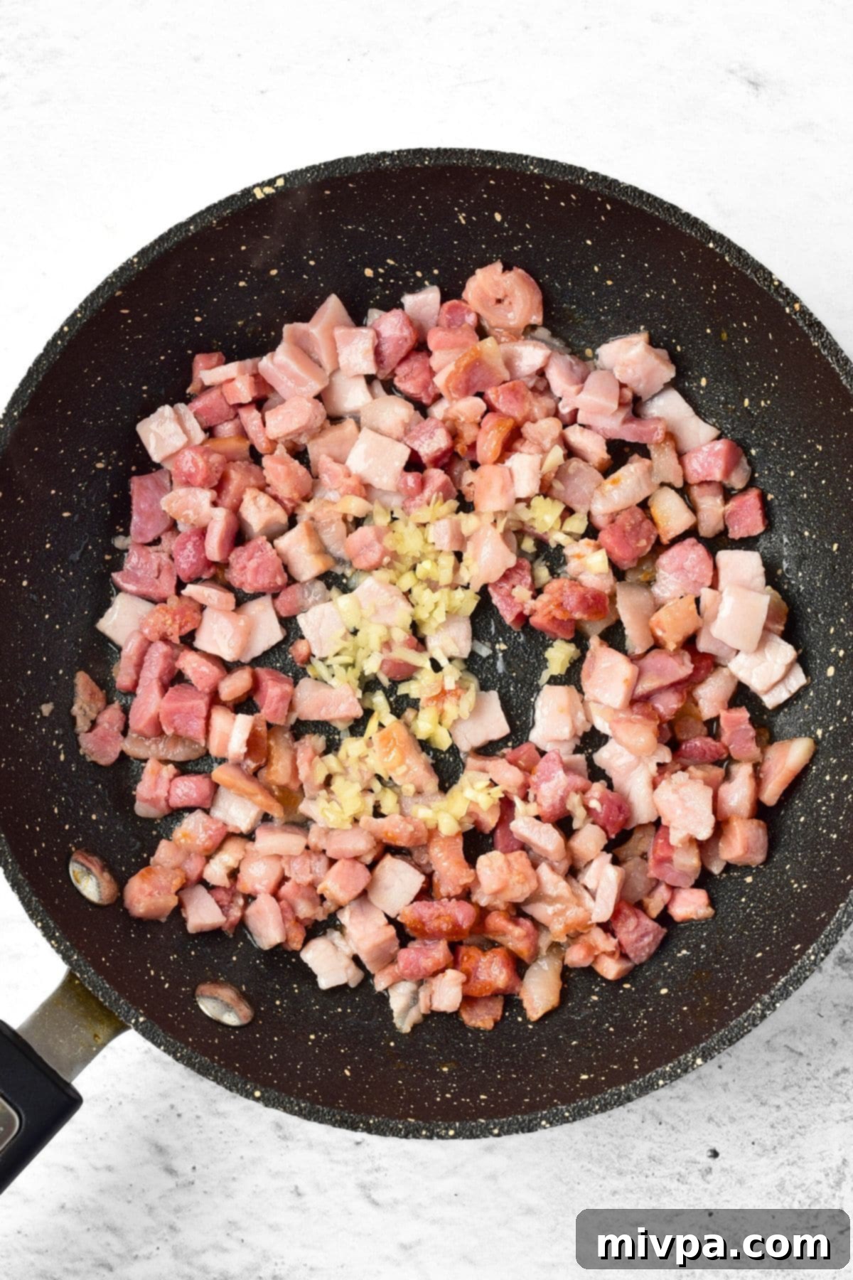 Luxurious Gluten and Dairy Free Pumpkin Carbonara 2 A skillet with diced pancetta sizzling with minced garlic.