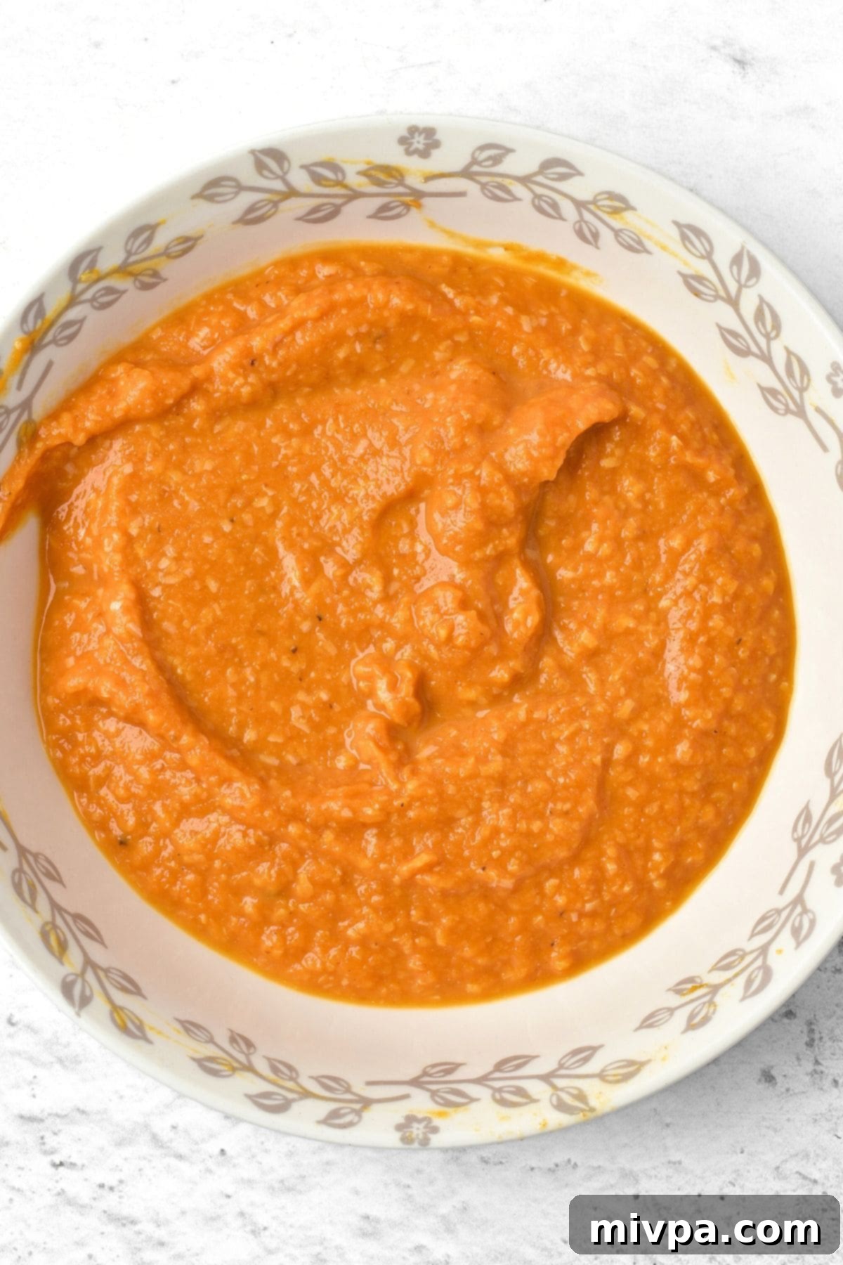 How to Make Pumpkin Carbonara Sauce A bowl of creamy orange pumpkin carbonara sauce being whisked.