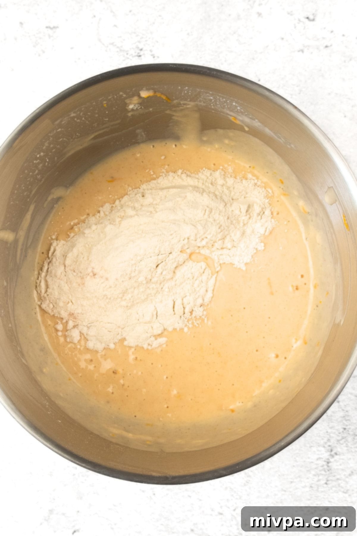 Gluten-Free Cranberry Orange Muffin Recipe (Dairy-Free) Flour mixture carefully added on top of the yellow wet batter.