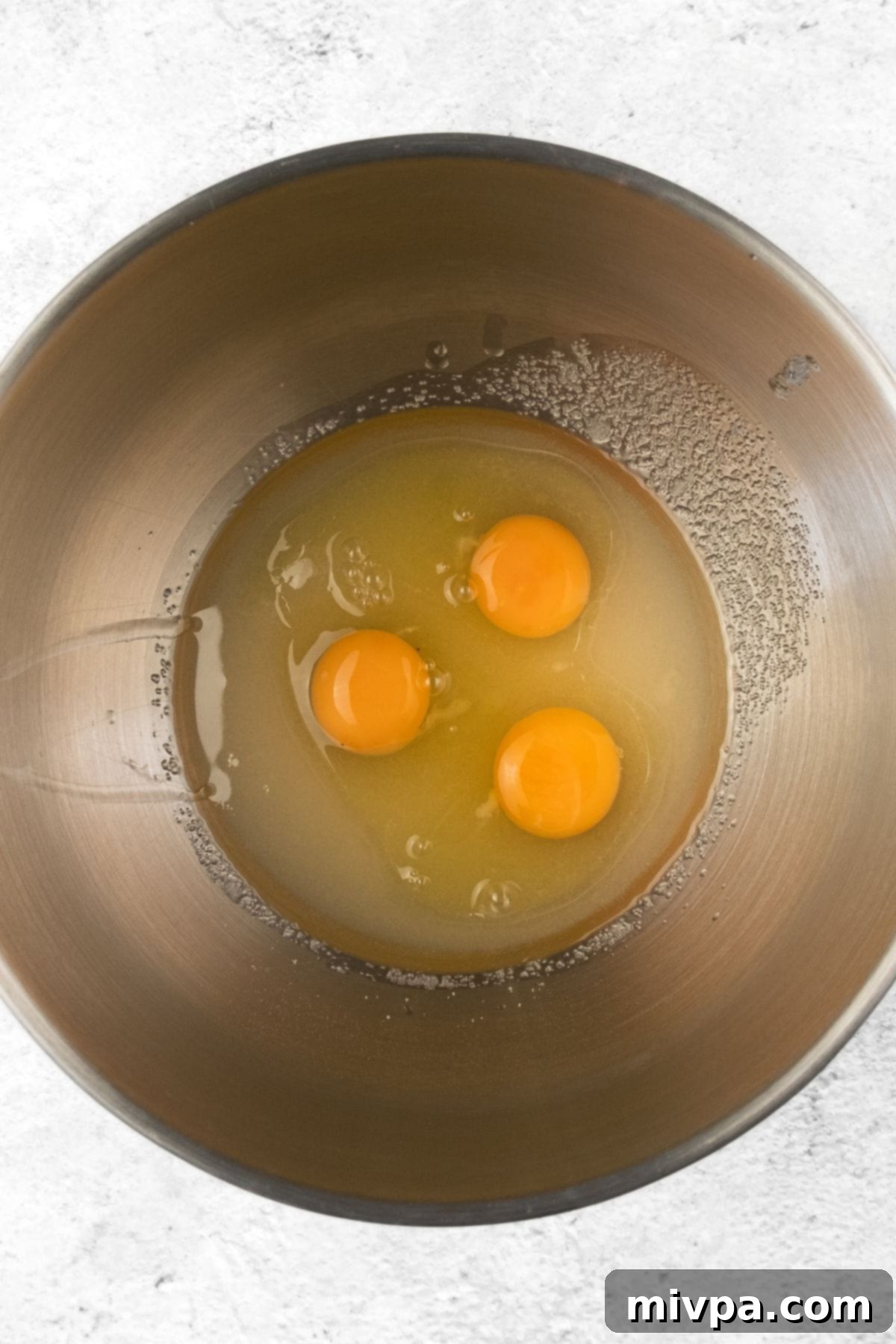 Orange Cranberry Muffins (Gluten-Free, Dairy-Free) Eggs, oil, and sugar being whisked together in a metal bowl.