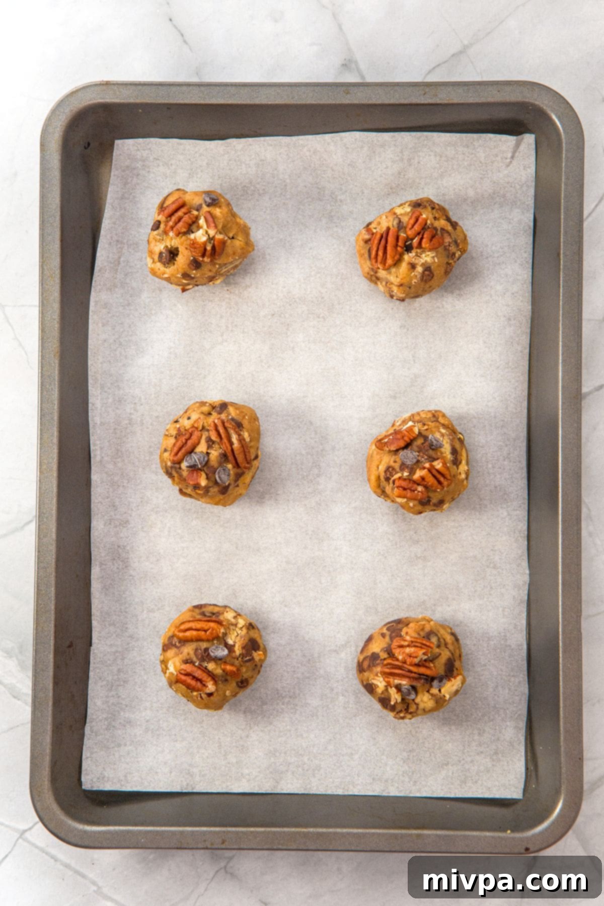 Browned Butter Pecan Chocolate Chip Cookies (Gluten-Free) Portioned cookie dough balls placed on a parchment-lined baking sheet.