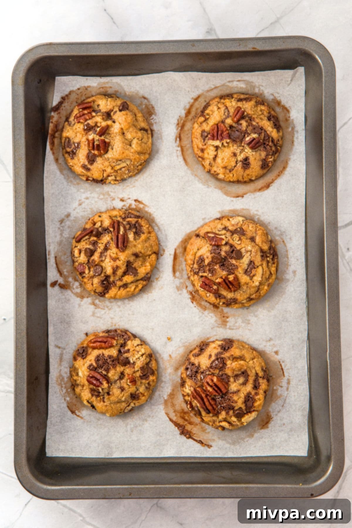 Gluten-Free Pecan Chocolate Chip Cookies Freshly baked cookies cooling on parchment paper after coming out of the oven.